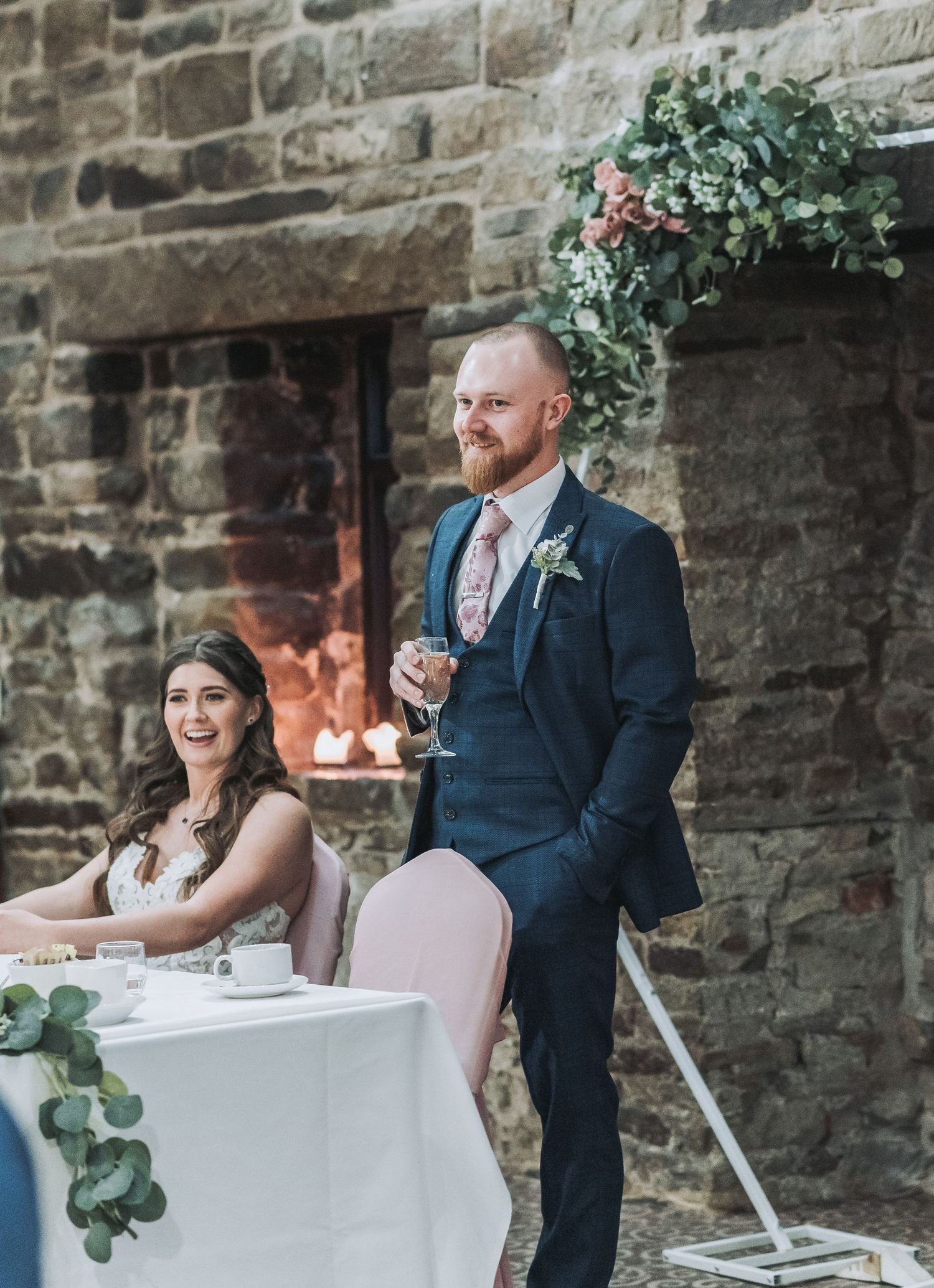 Reception moment at rustic stone venue with elegant table setting and candlelight.