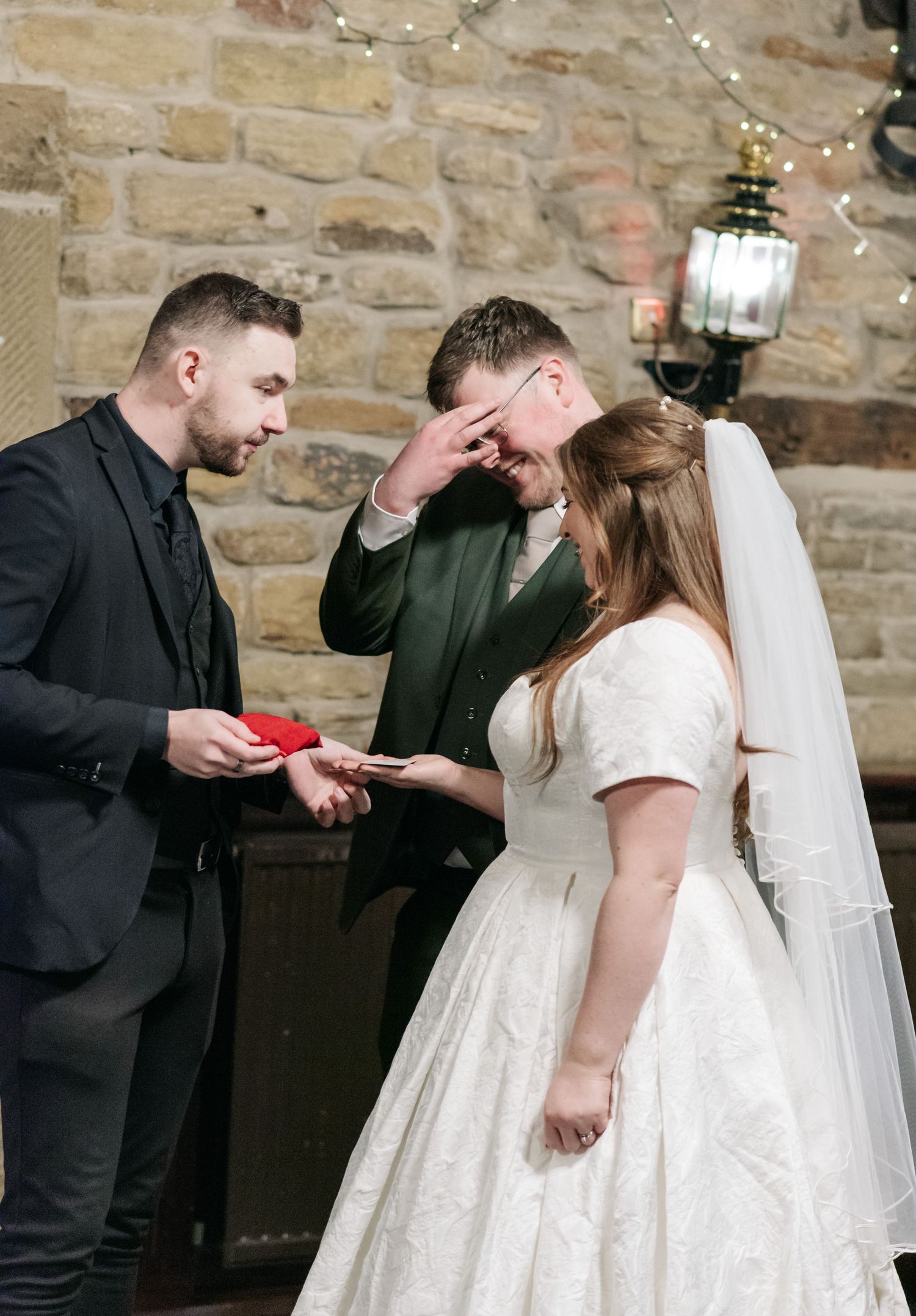 Wedding party members interact during a candid moment at the stone-walled reception venue.