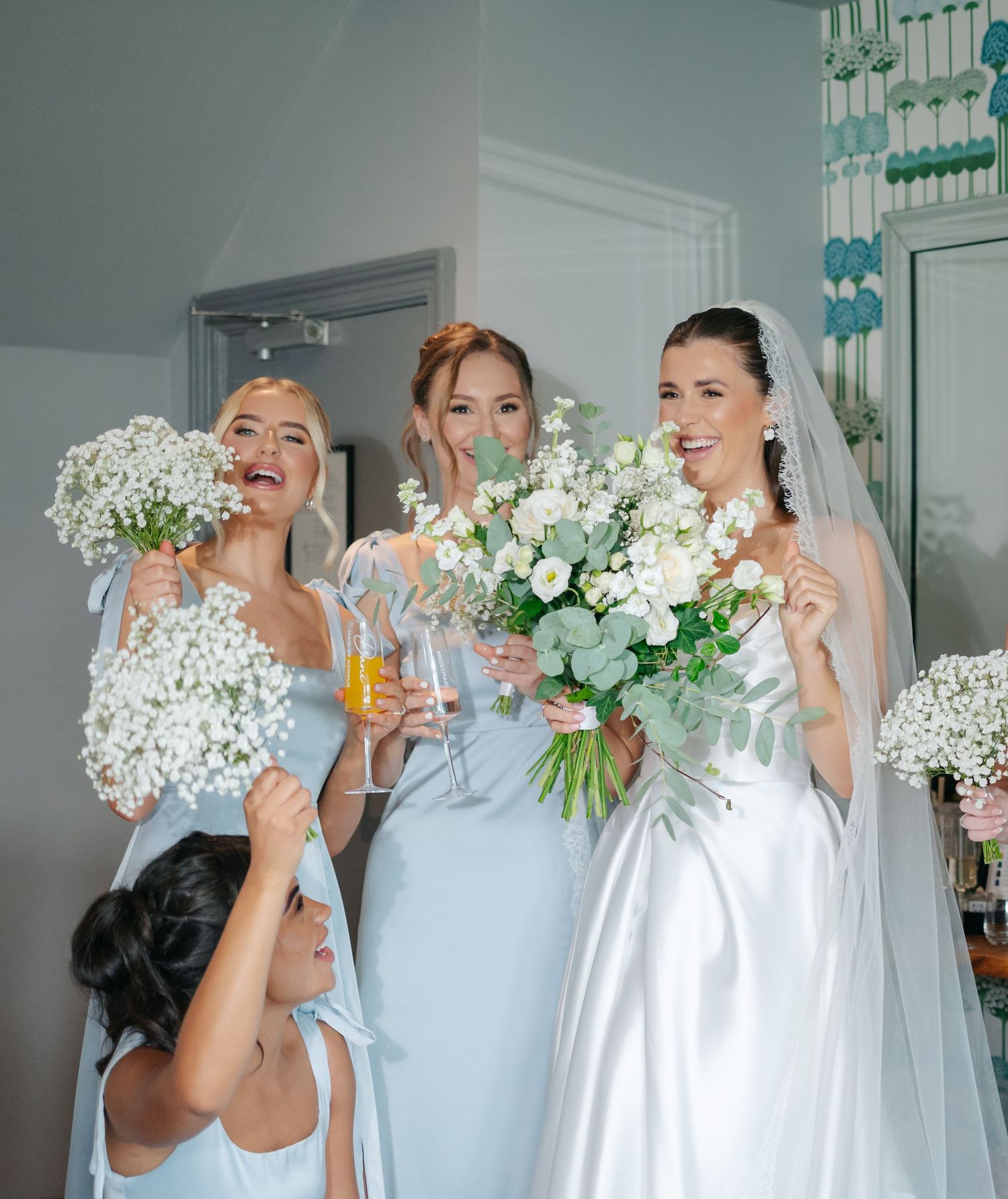 Bridesmaids in light blue dresses hold white flower bouquets during wedding celebrations.
