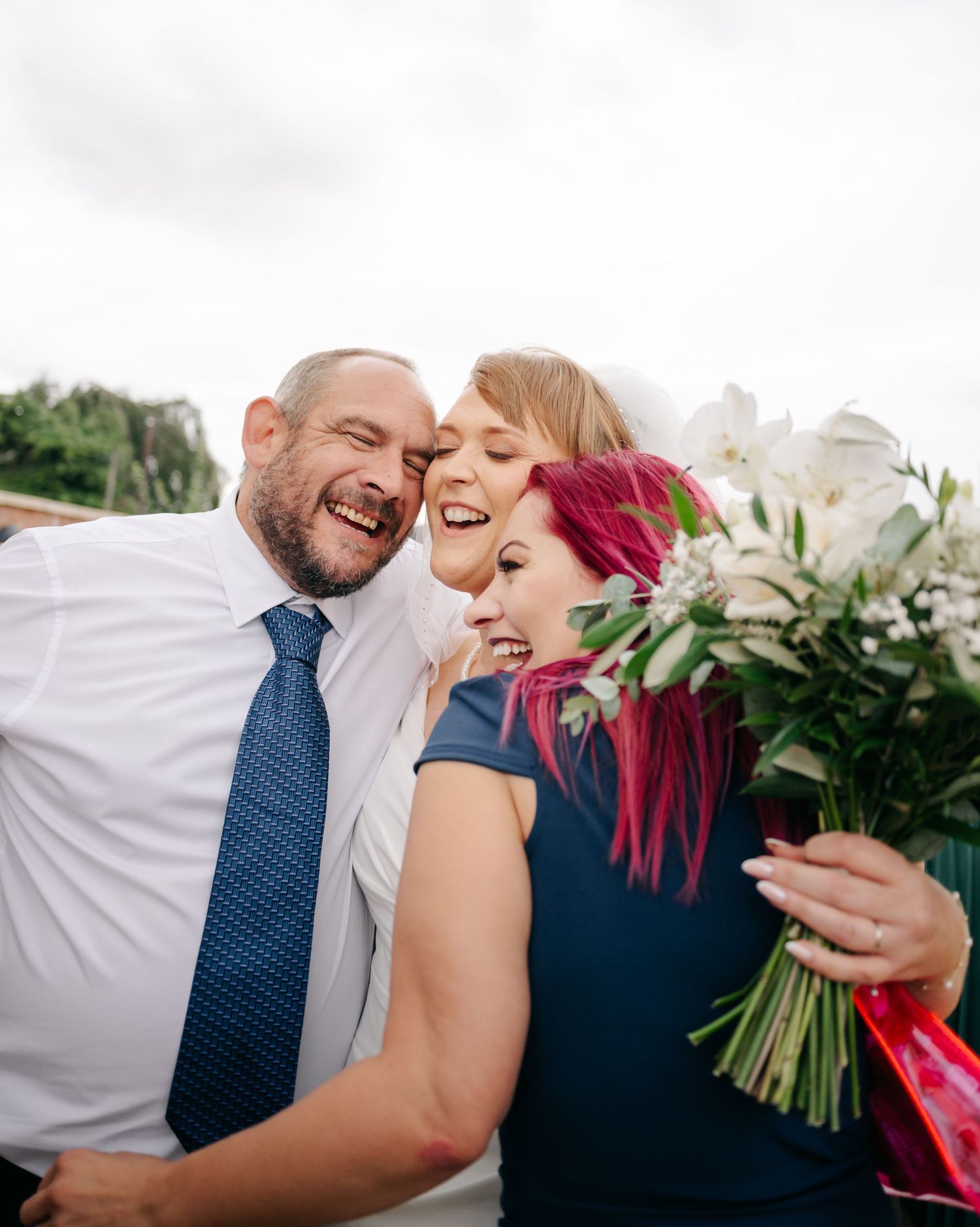 A joyful wedding moment captured outdoors with a beautiful white floral bouquet.
