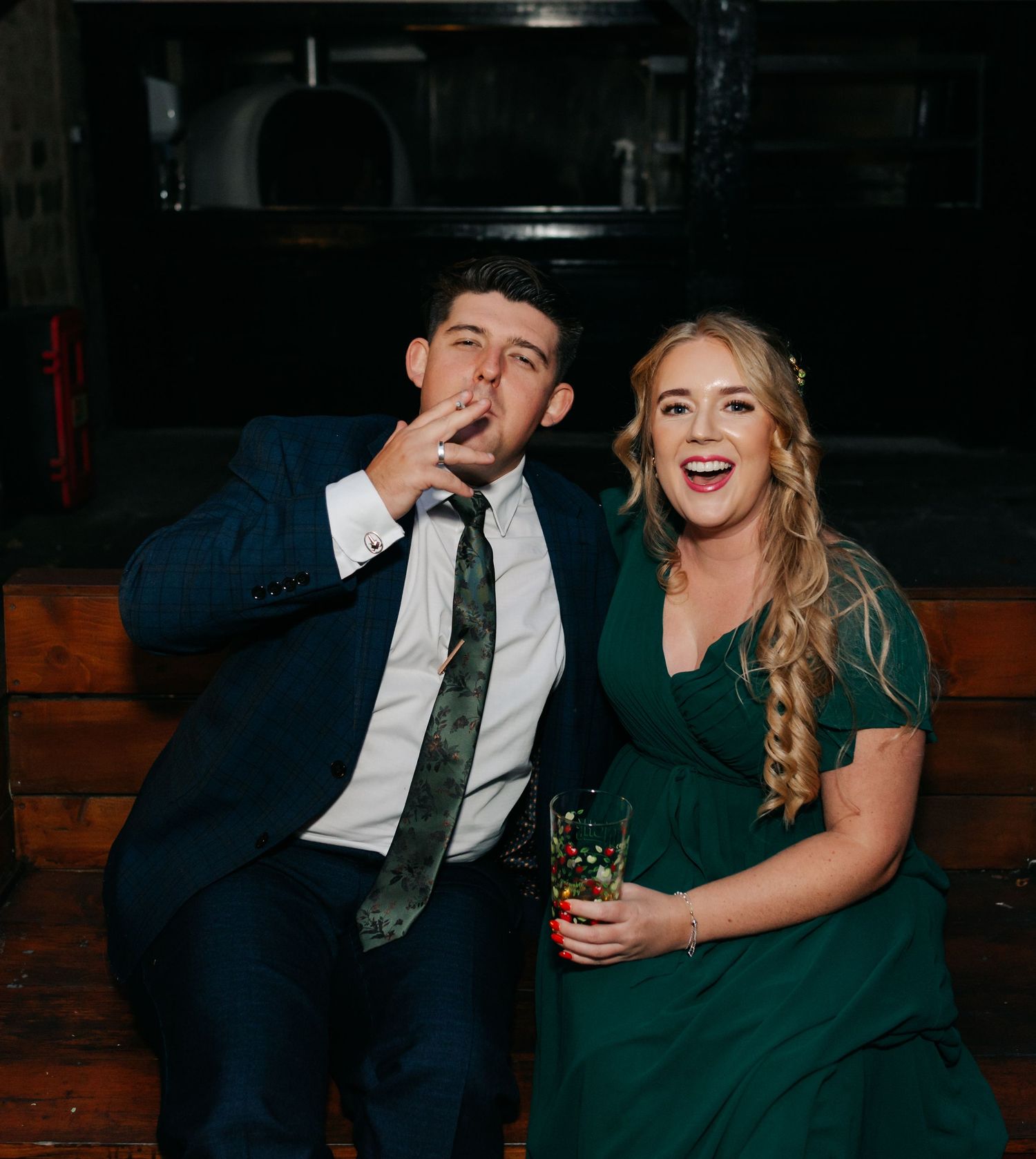 Couple sharing a laugh at wedding reception while dressed in formal attire.