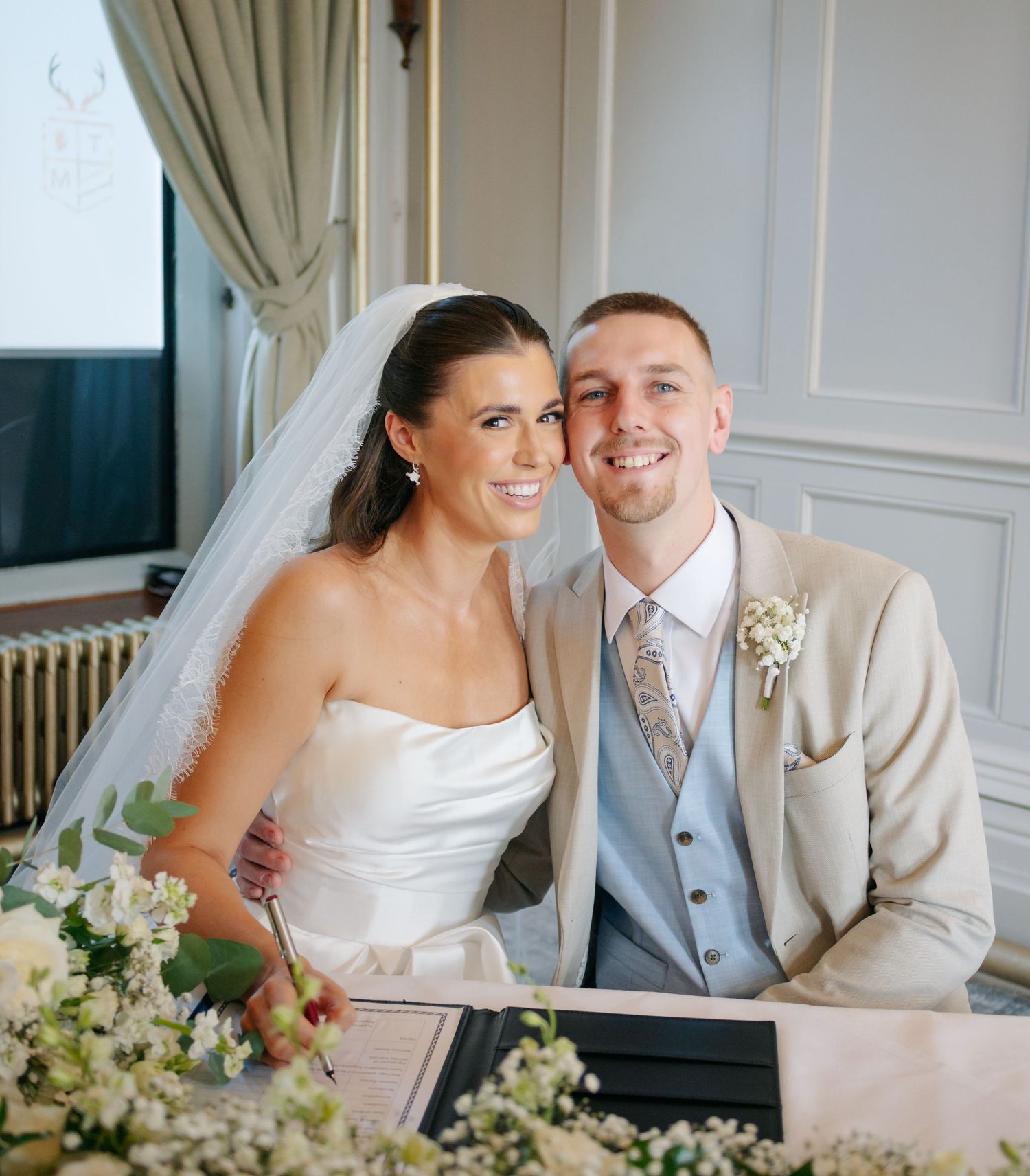 Newlyweds share intimate moments in an elegant room with white and beige decor.