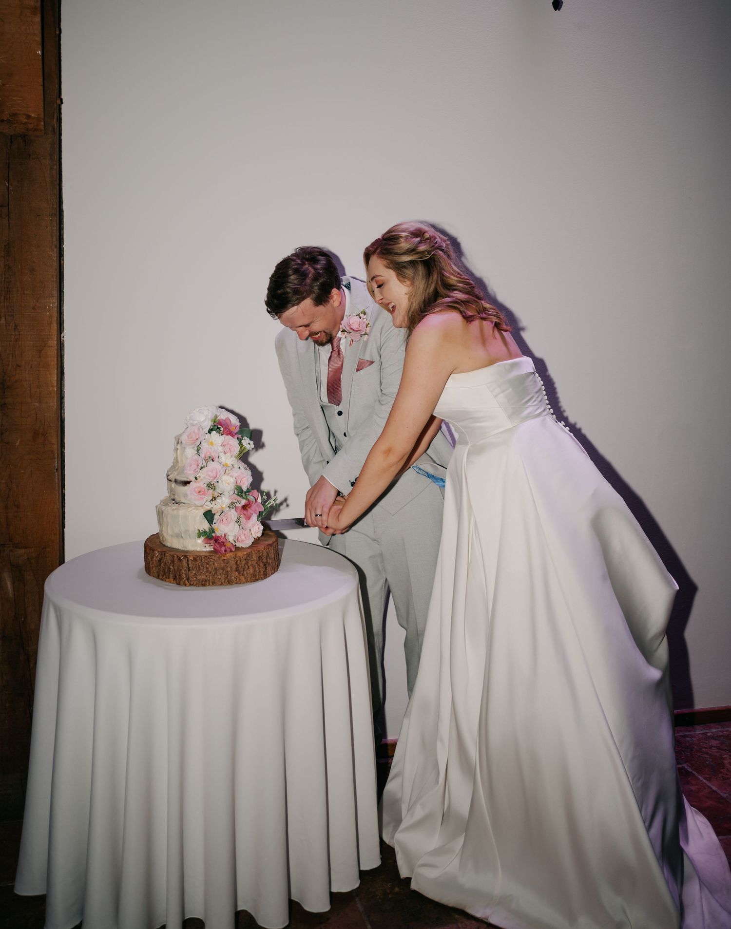 Couple cutting their floral-decorated wedding cake at reception.