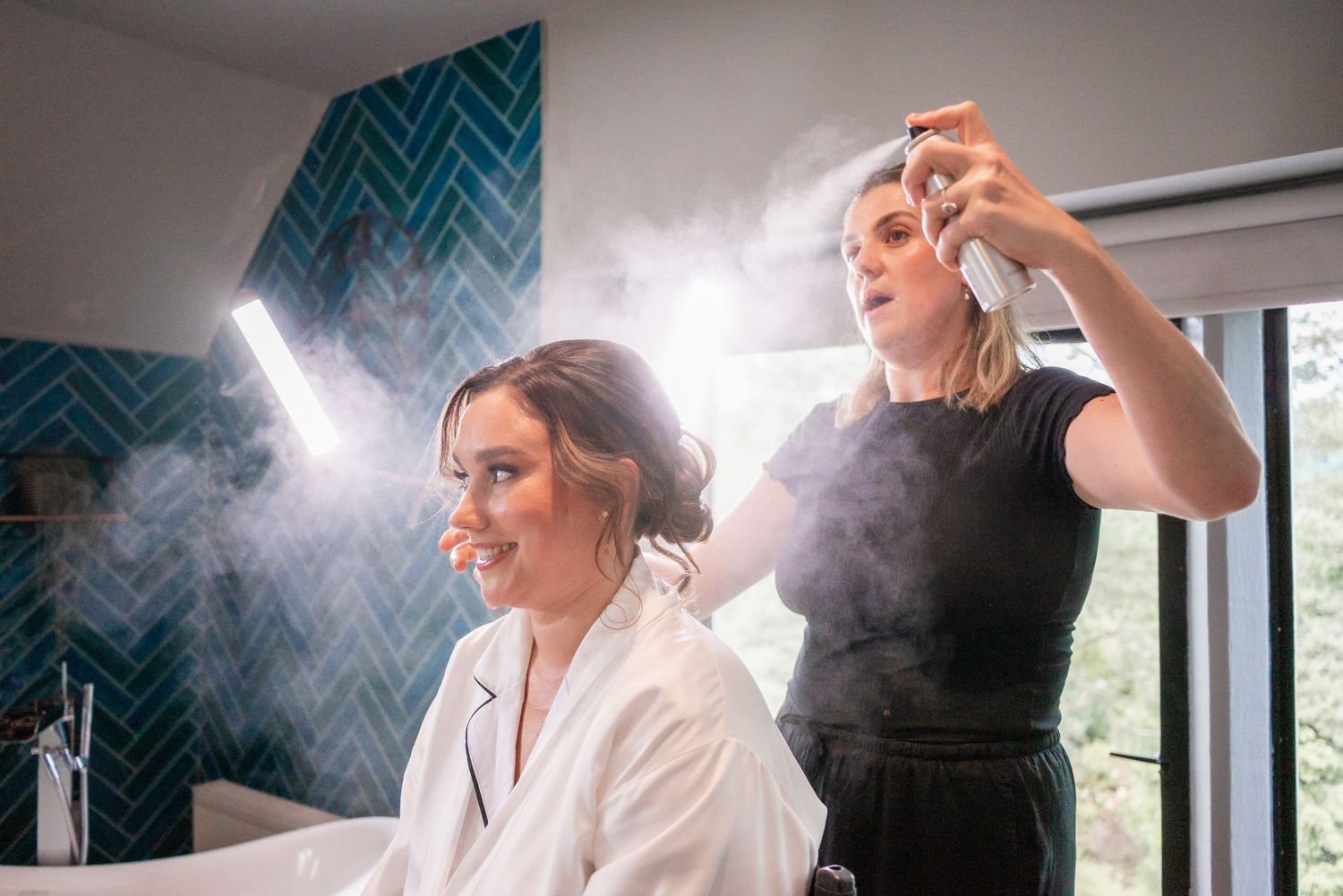 Wedding preparation scene with hairspray and styling in progress against chevron patterned backdrop.
