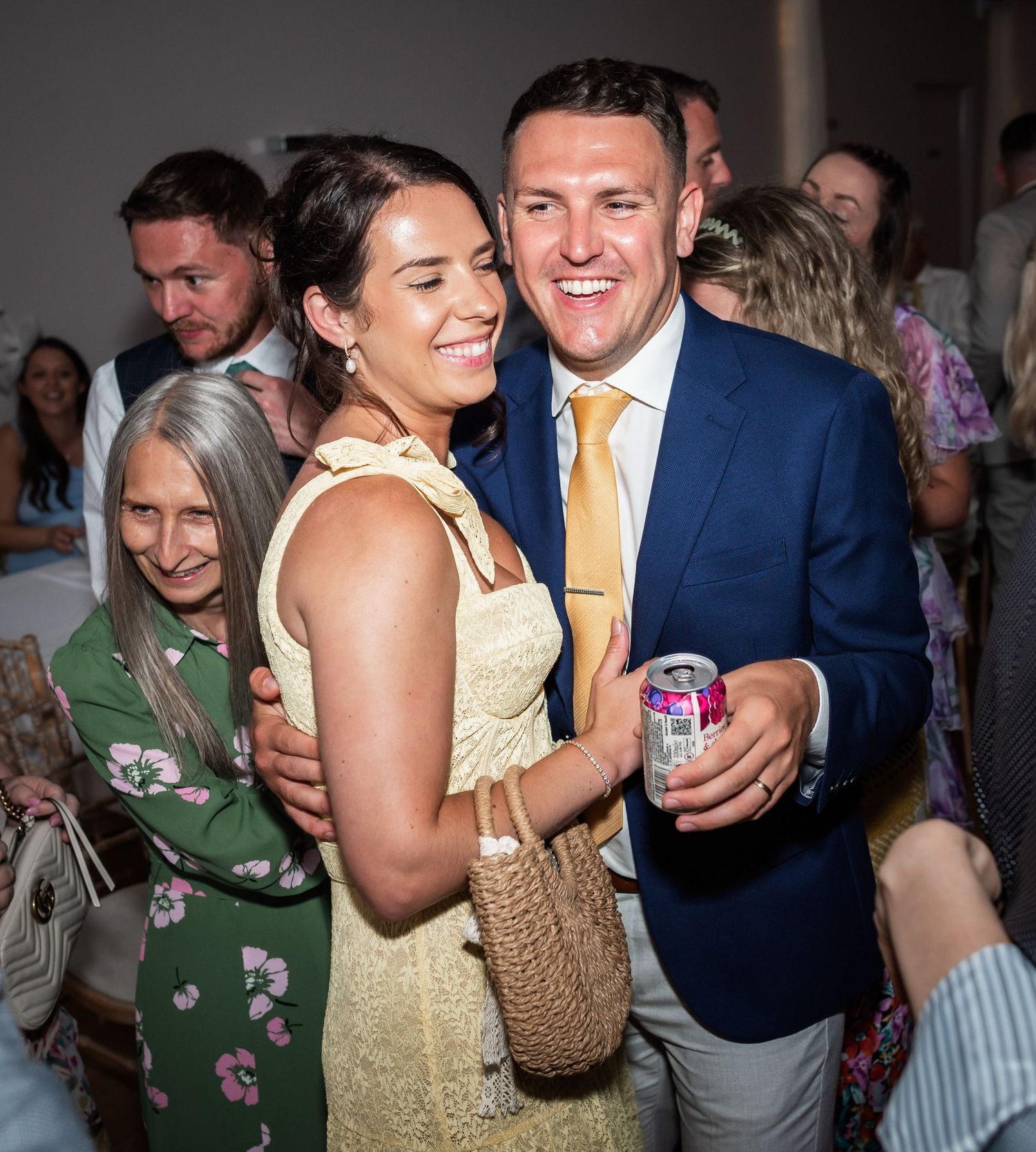 A couple shares a joyful moment at a wedding reception, with the woman in a yellow dress and man in a blue blazer.