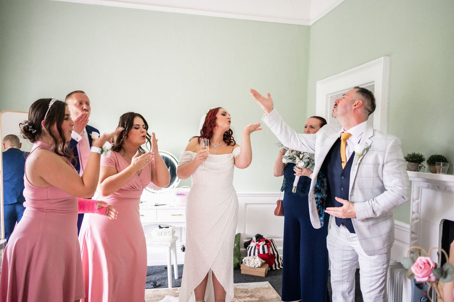 Wedding party celebrates with joyful expressions and gestures during reception.