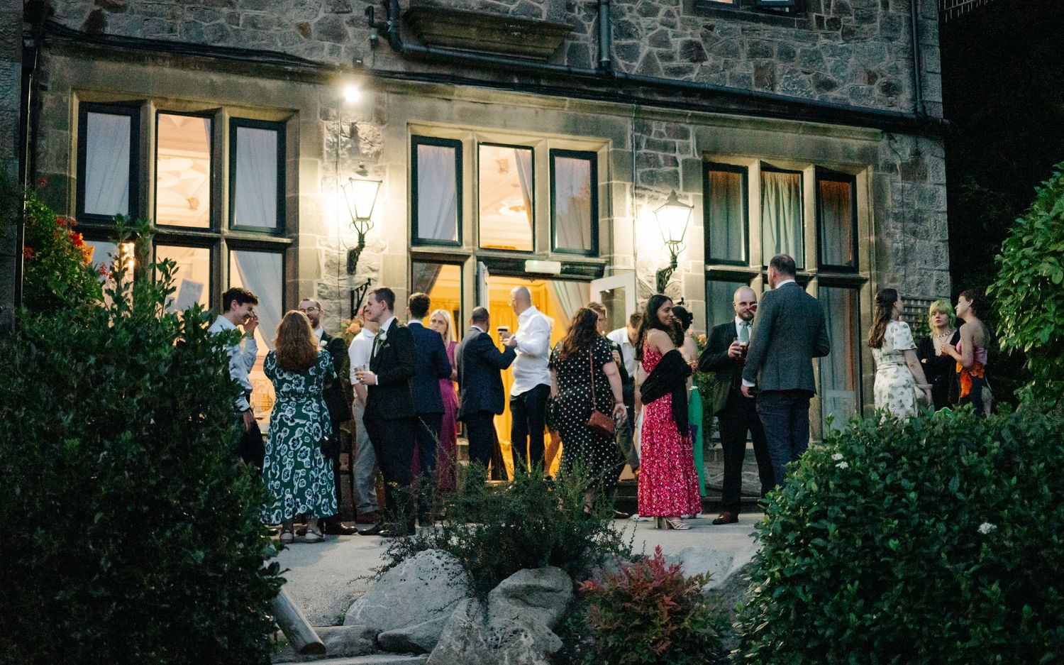 Evening wedding venue exterior with stone walls and illuminated windows.