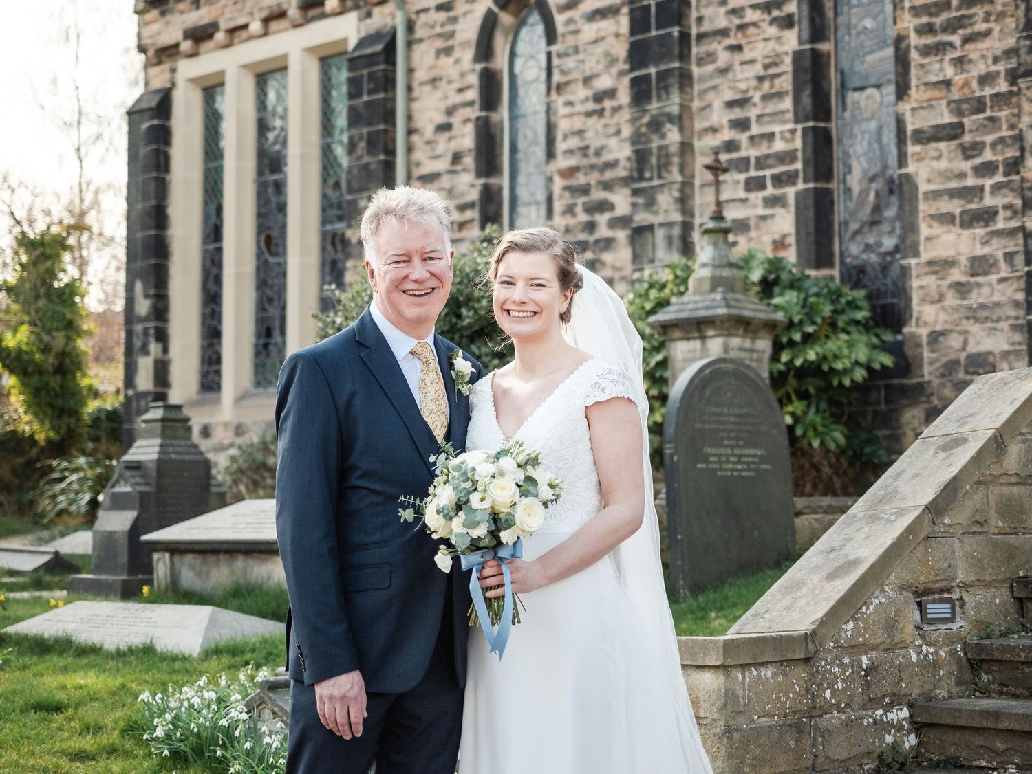Wedding couple posing for portraits outside a historic stone church building.