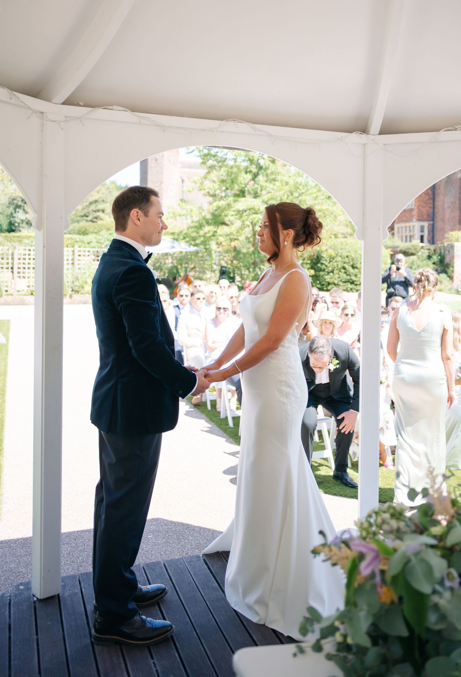 Couple shares their first dance under an elegant white gazebo surrounded by wedding guests.