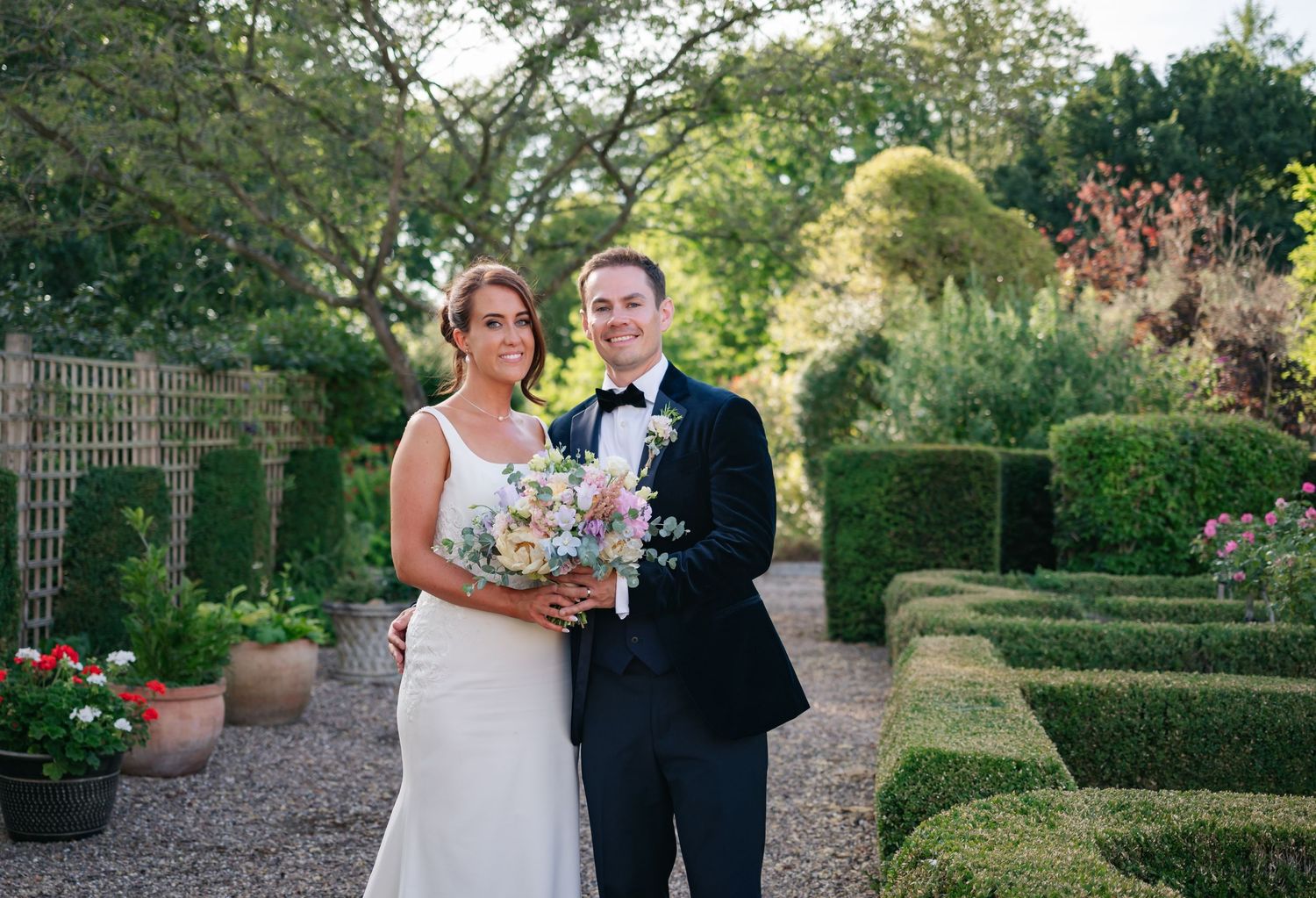 Wedding couple posing for portraits in a manicured garden setting.