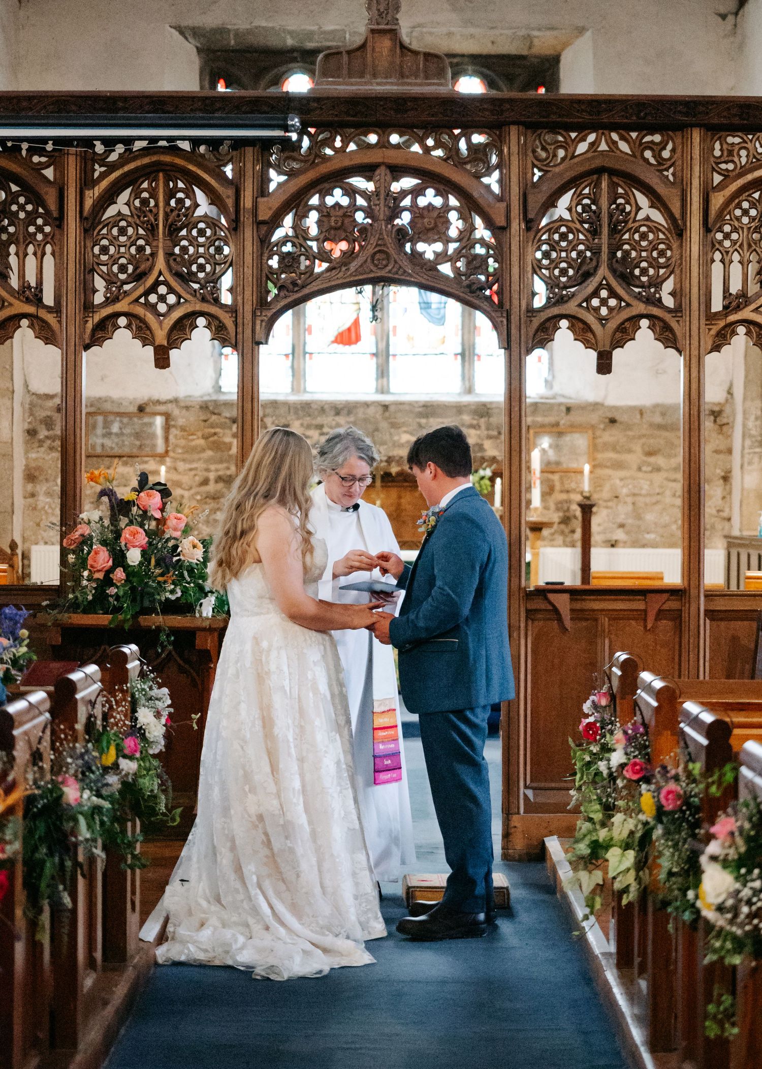 Traditional church wedding ceremony with ornate wooden screens and floral decorations.