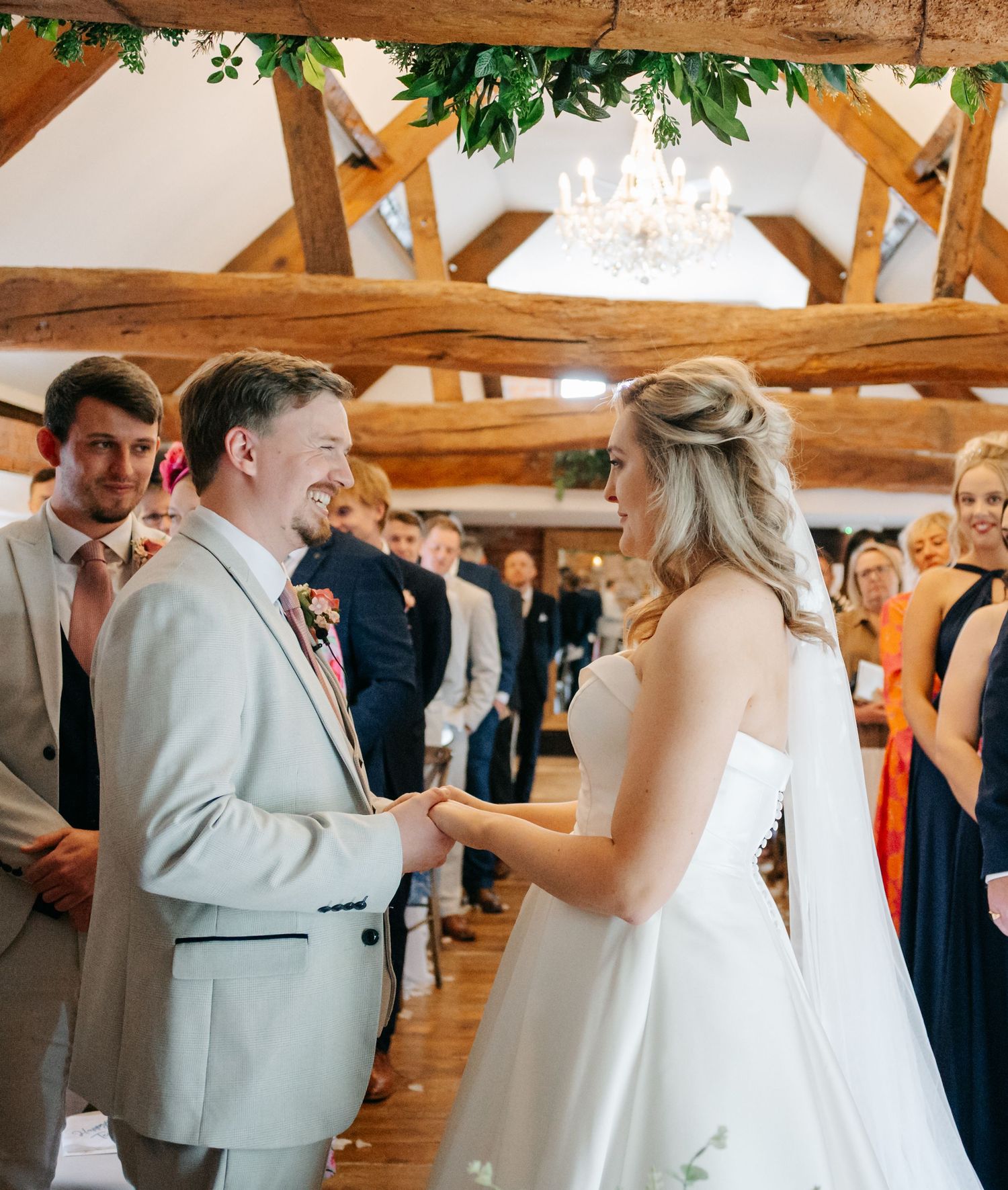 Wedding celebration in a rustic barn venue with exposed wooden beams and greenery decorations.