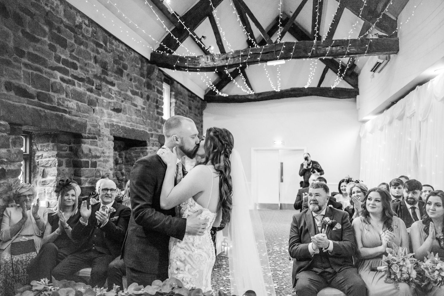 Wedding ceremony in a rustic venue with exposed brick walls and wooden beams.