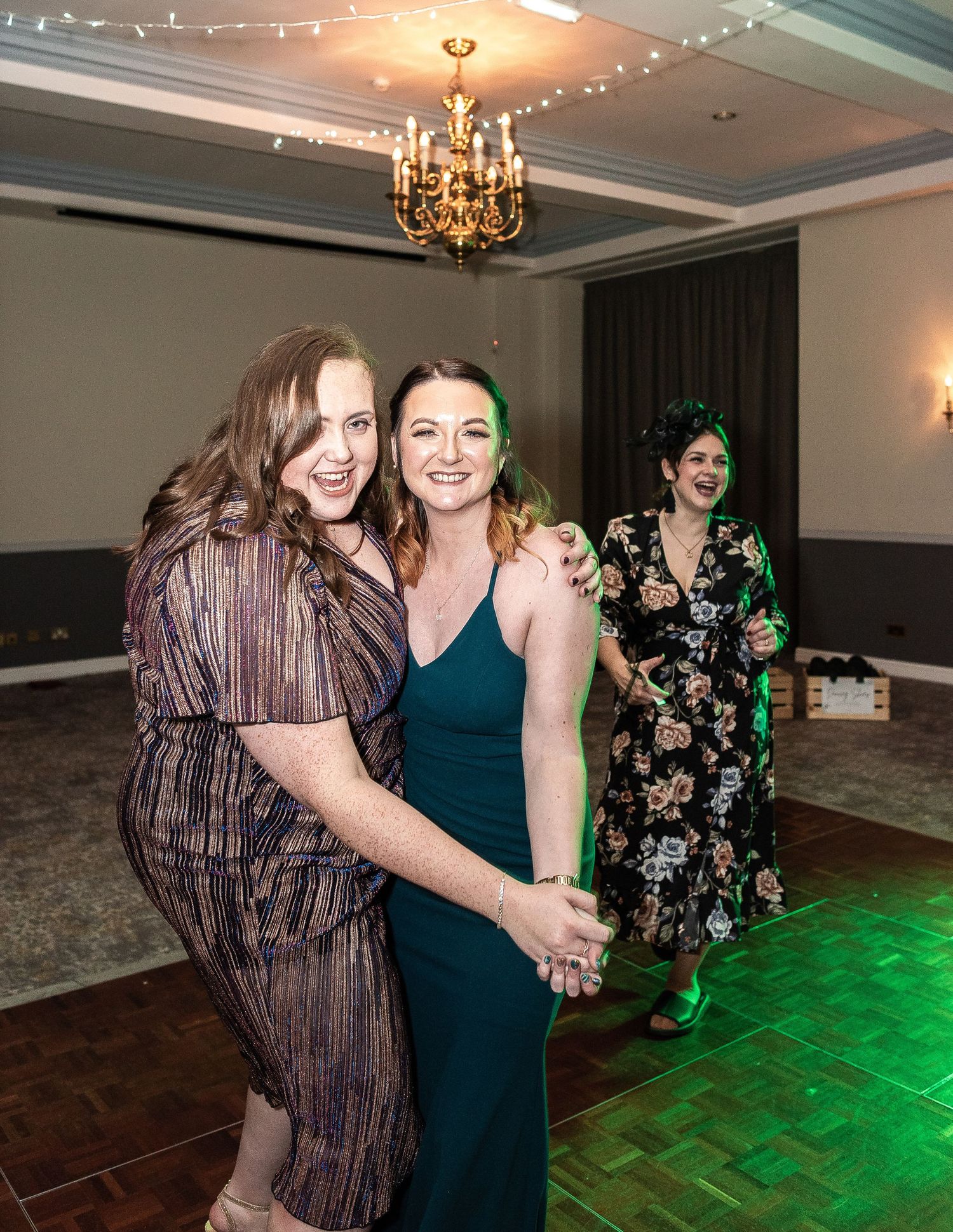 Dancing guests enjoying themselves on illuminated dance floor with chandelier overhead.