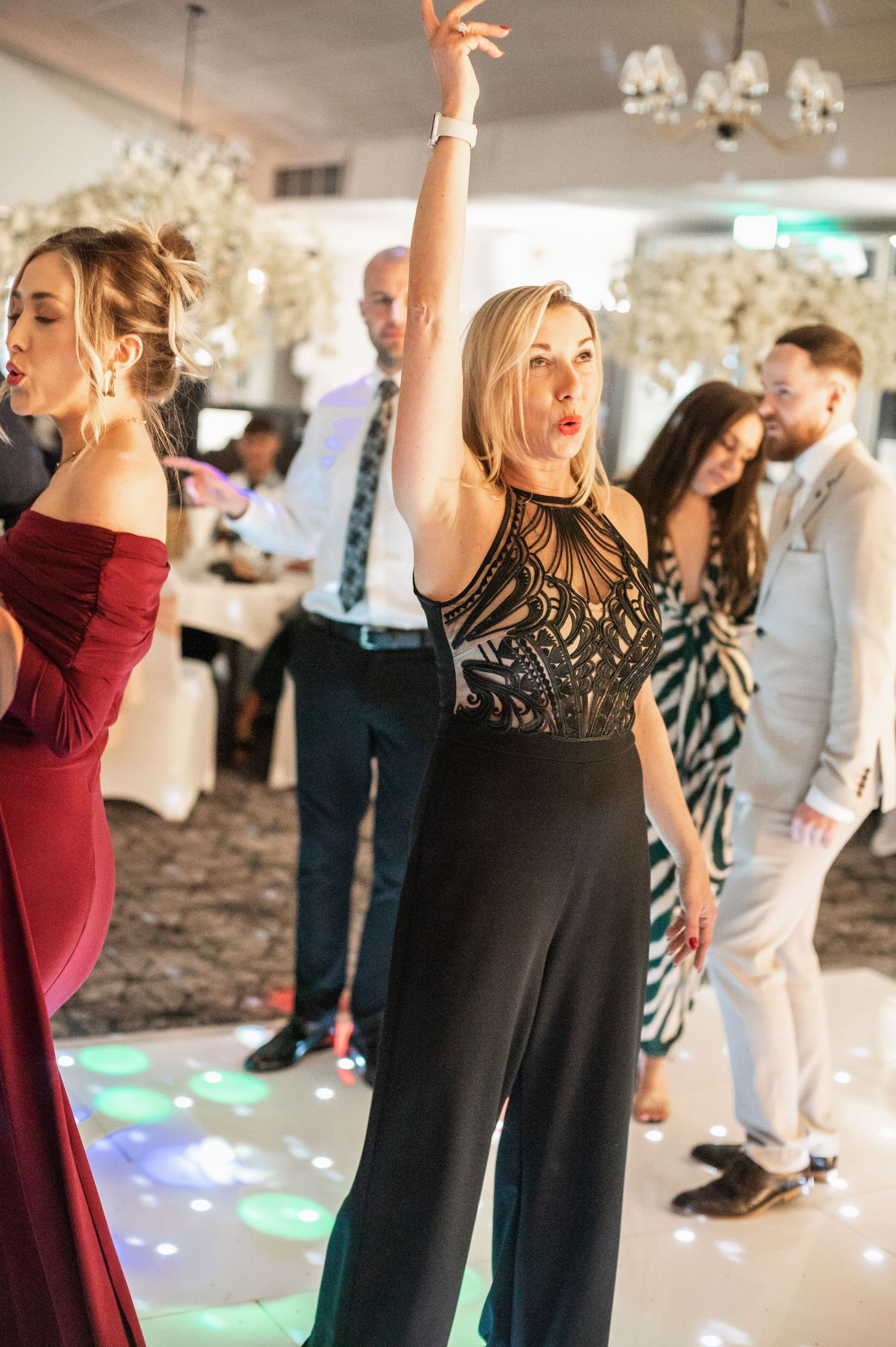 Wedding guests dancing and celebrating on a decorated dance floor with festive lighting.