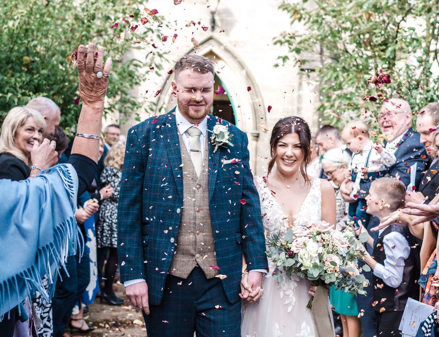 Celebratory moment outside a chapel with confetti being tossed in the air.