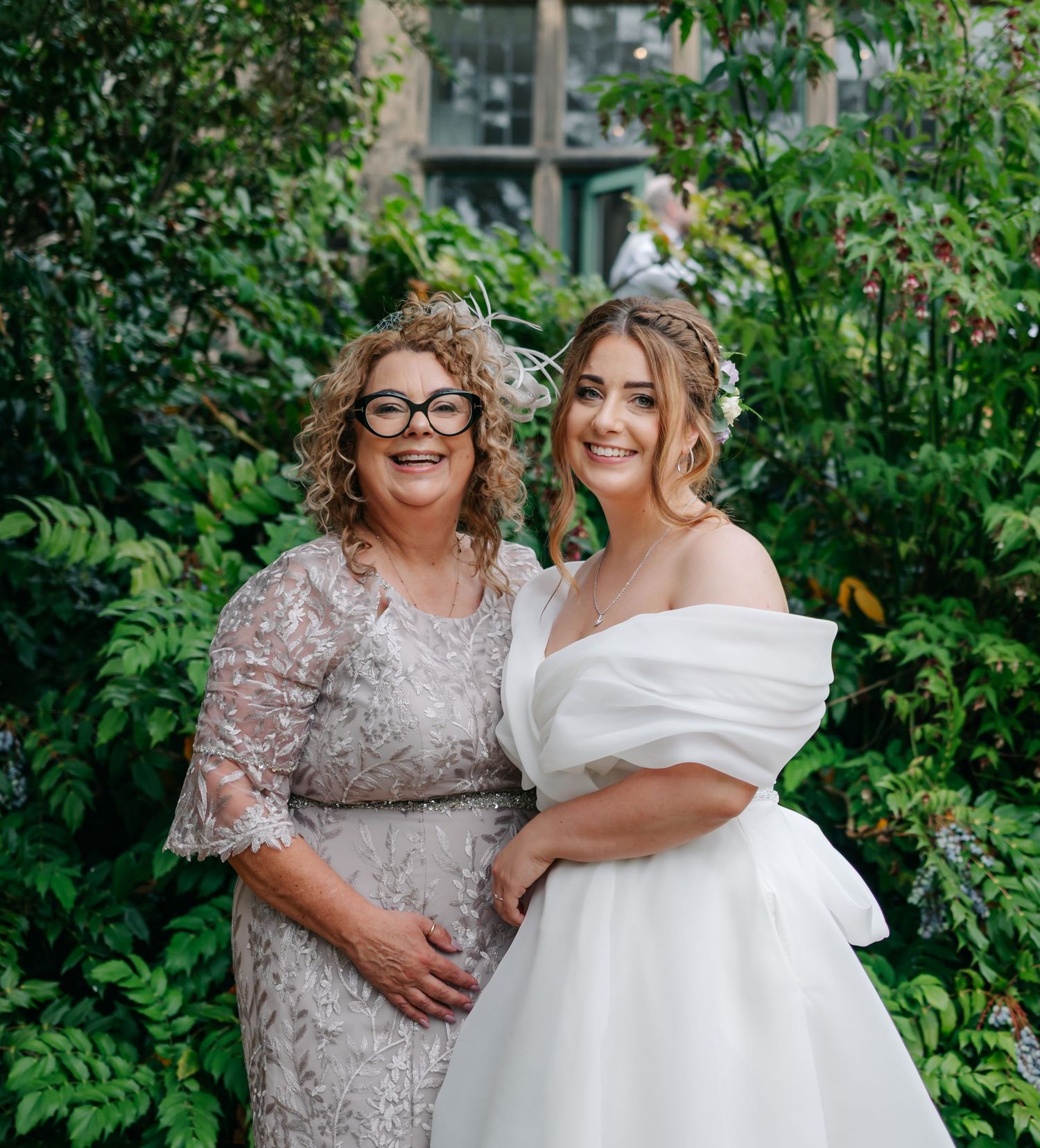 Garden wedding portrait against lush greenery backdrop with floral accents.