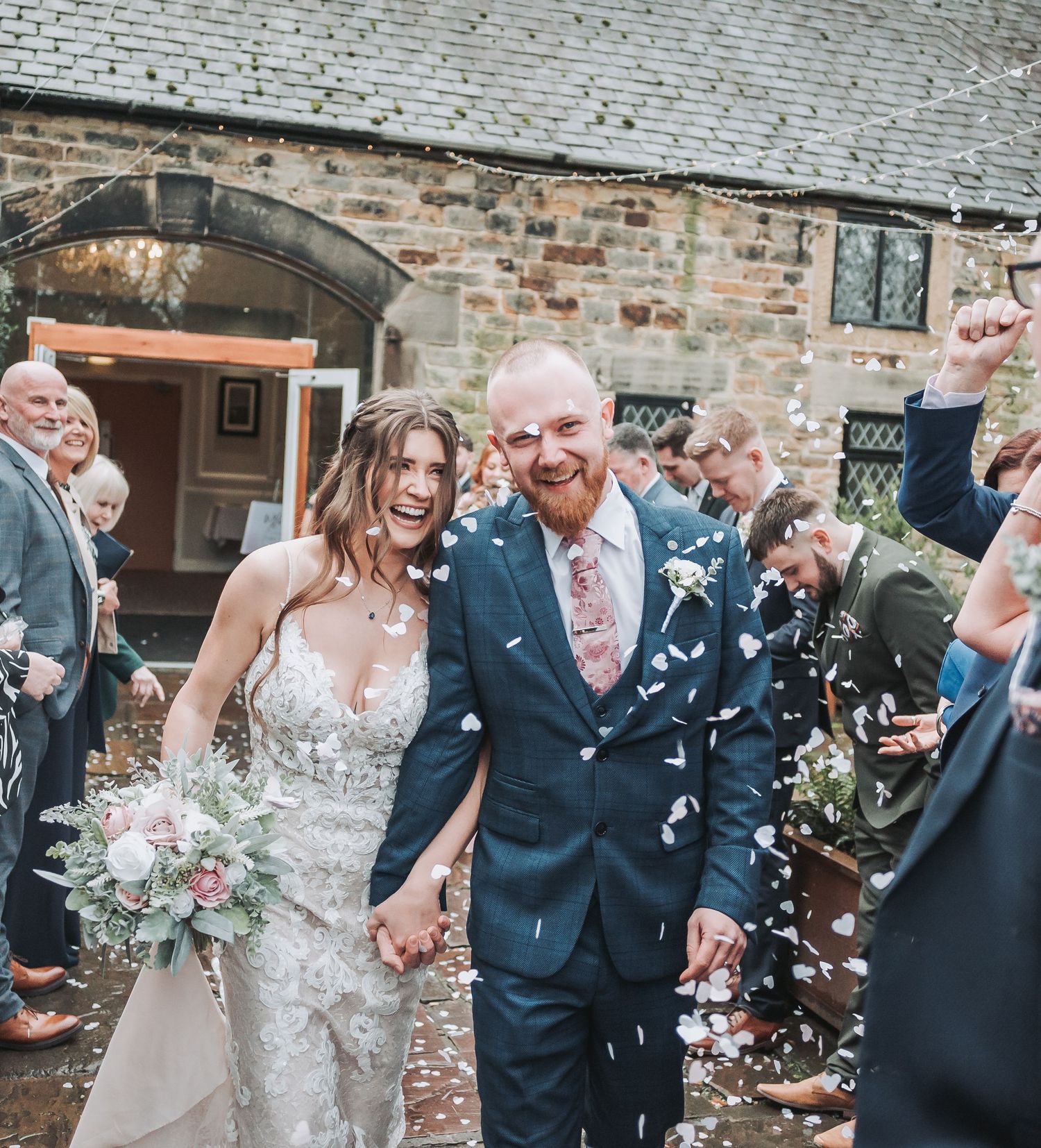 A celebratory wedding moment with confetti falling outside a historic brick building.