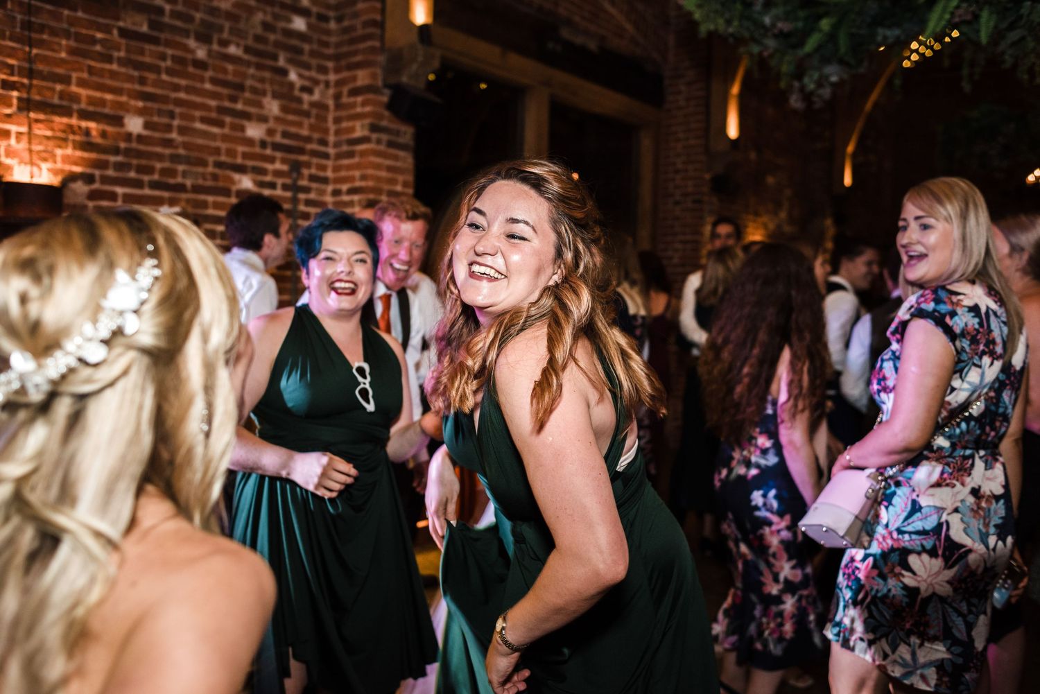 Wedding guests dance and laugh together during a lively reception celebration.