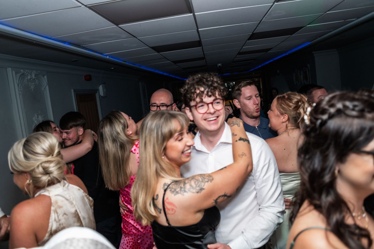 Energetic wedding reception dance floor filled with celebrating guests.