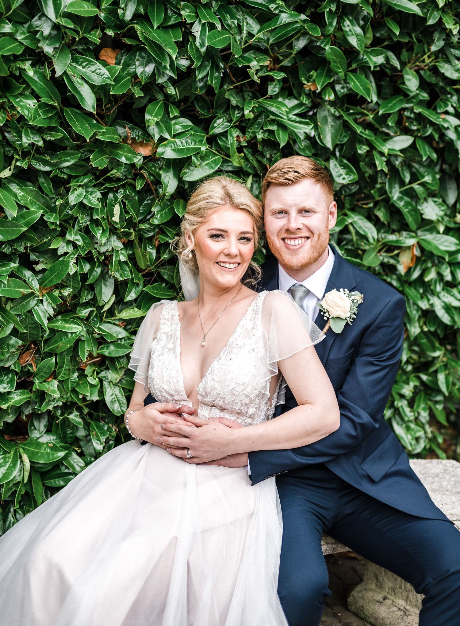 Romantic portrait against lush green foliage backdrop at elegant wedding.