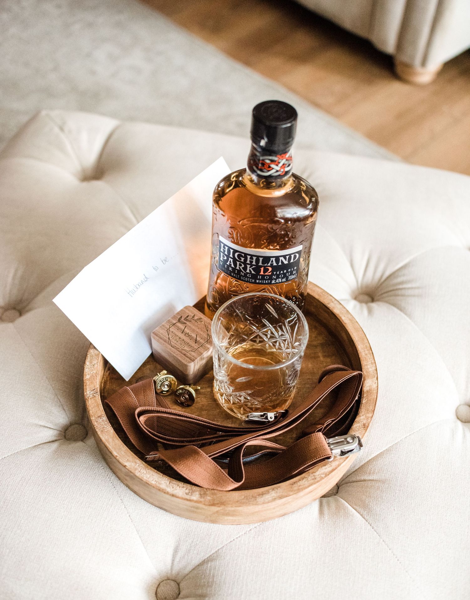 Bottle of bourbon with glass and accessories arranged on wooden serving tray.
