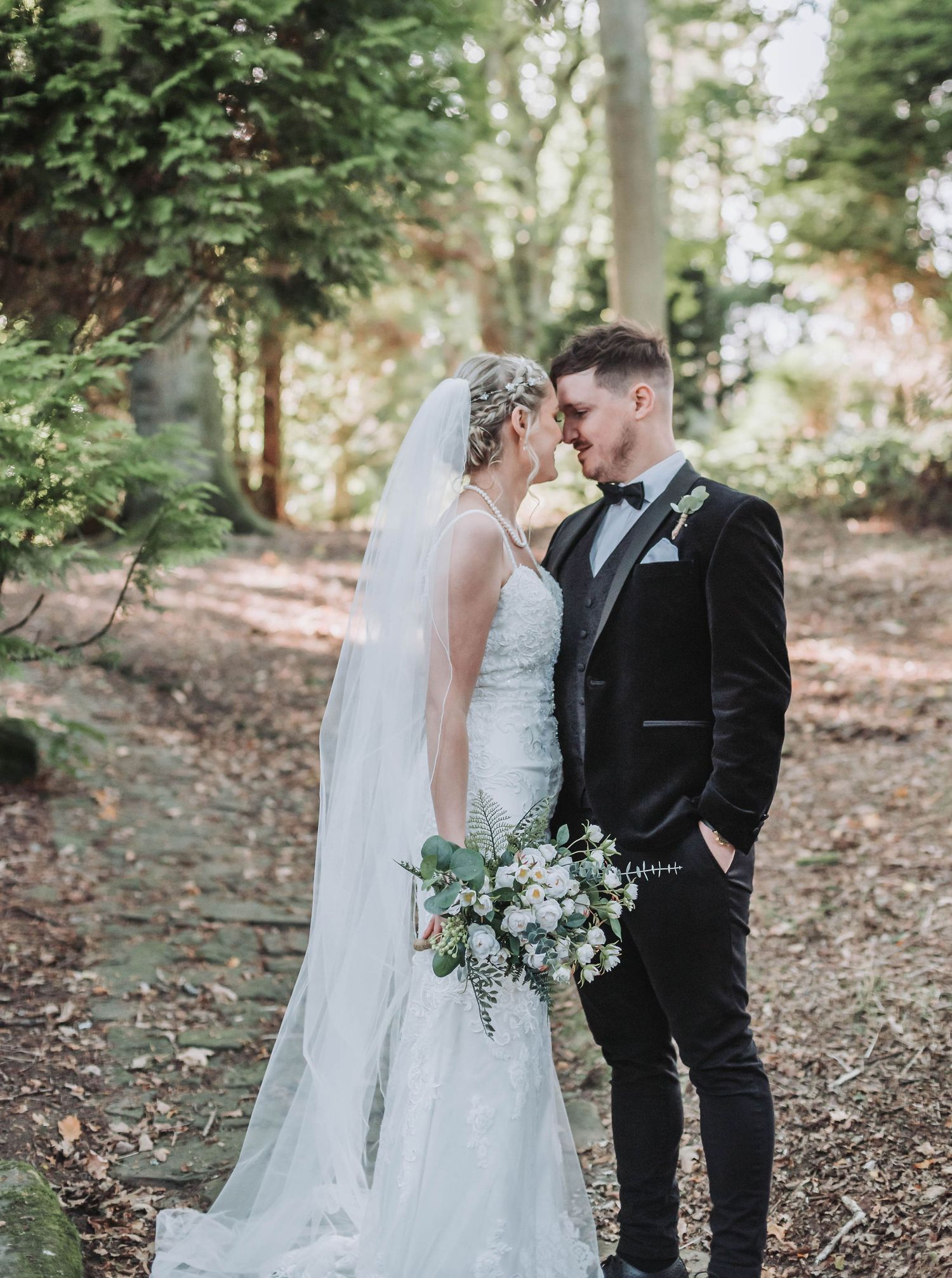 Intimate wedding portrait of a couple sharing a tender moment in a wooded forest setting.