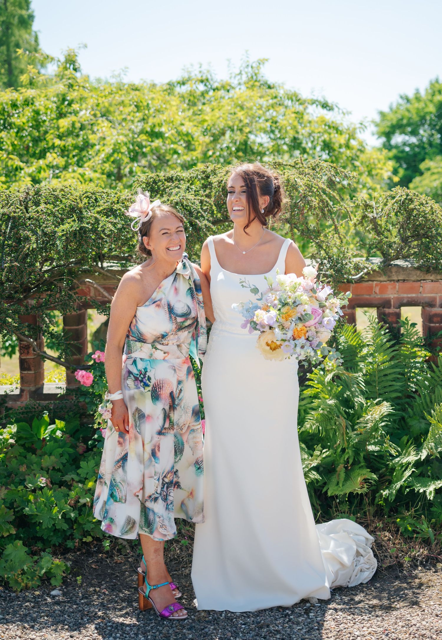 Garden wedding scene with floral dresses and bouquets against lush green landscaping.