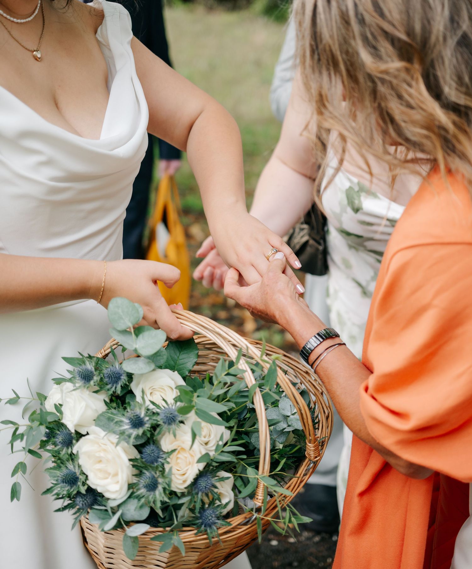 Close-up of hands arranging flowers and greenery in wicker baskets.