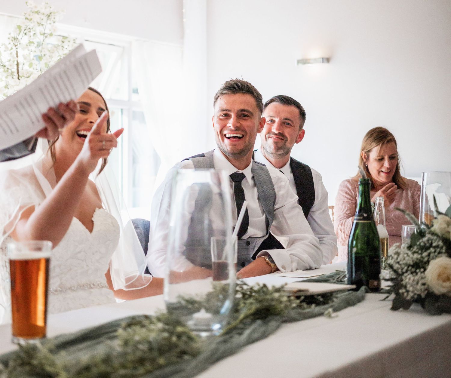 Celebratory moment at wedding reception with guests laughing around decorated table.