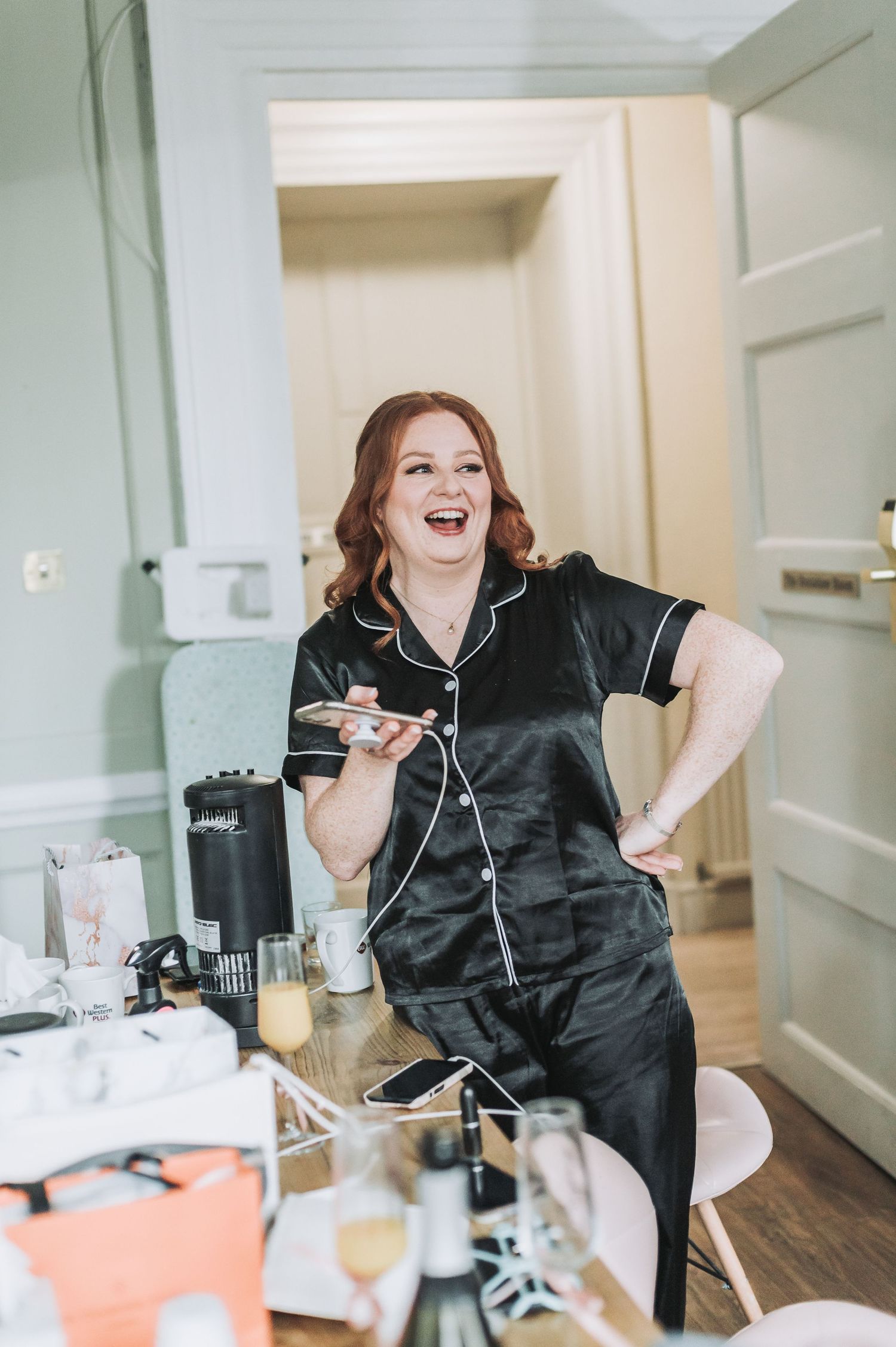 Someone wearing black silk pajamas laughs joyfully while getting ready in the morning.