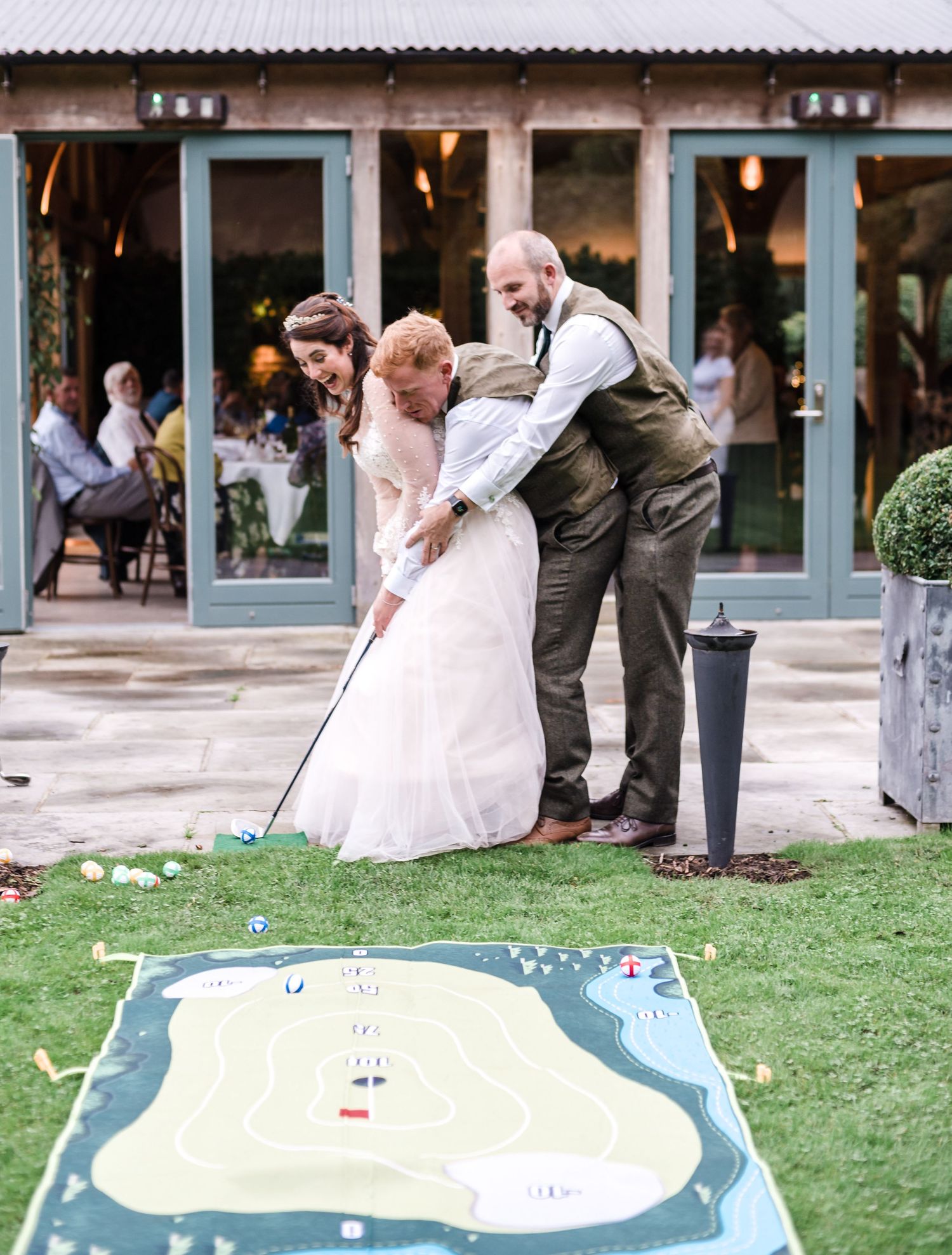 Wedding guests play mini golf on outdoor course during reception.