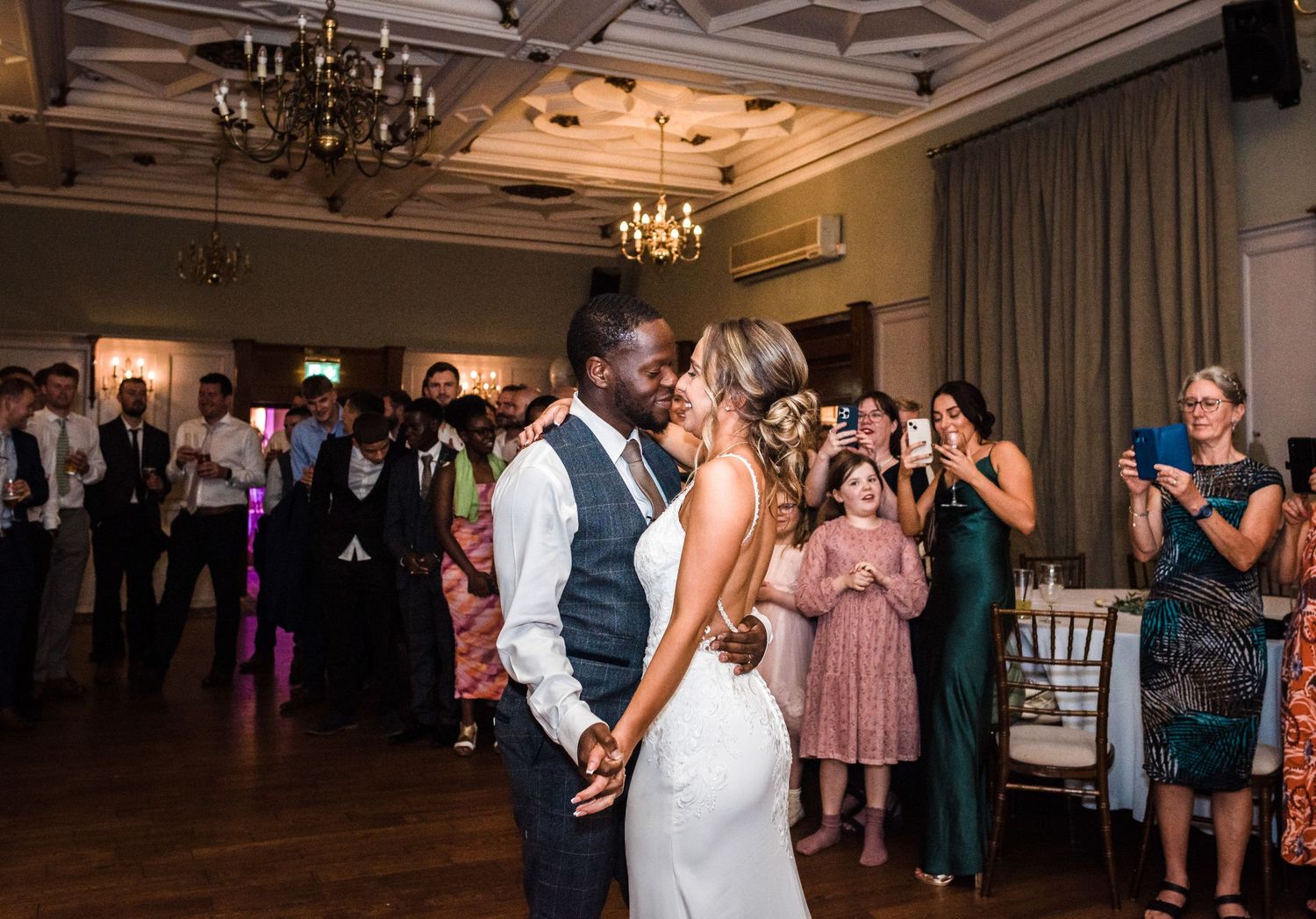 Guests watch couple share intimate dance moment at indoor reception venue.