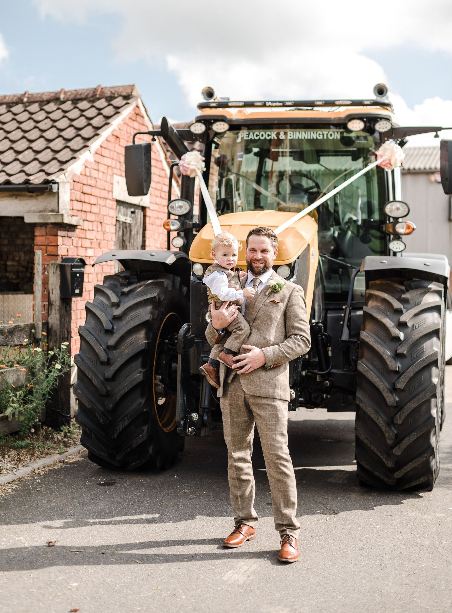 A large modern farm tractor displayed against residential buildings with brick walls.