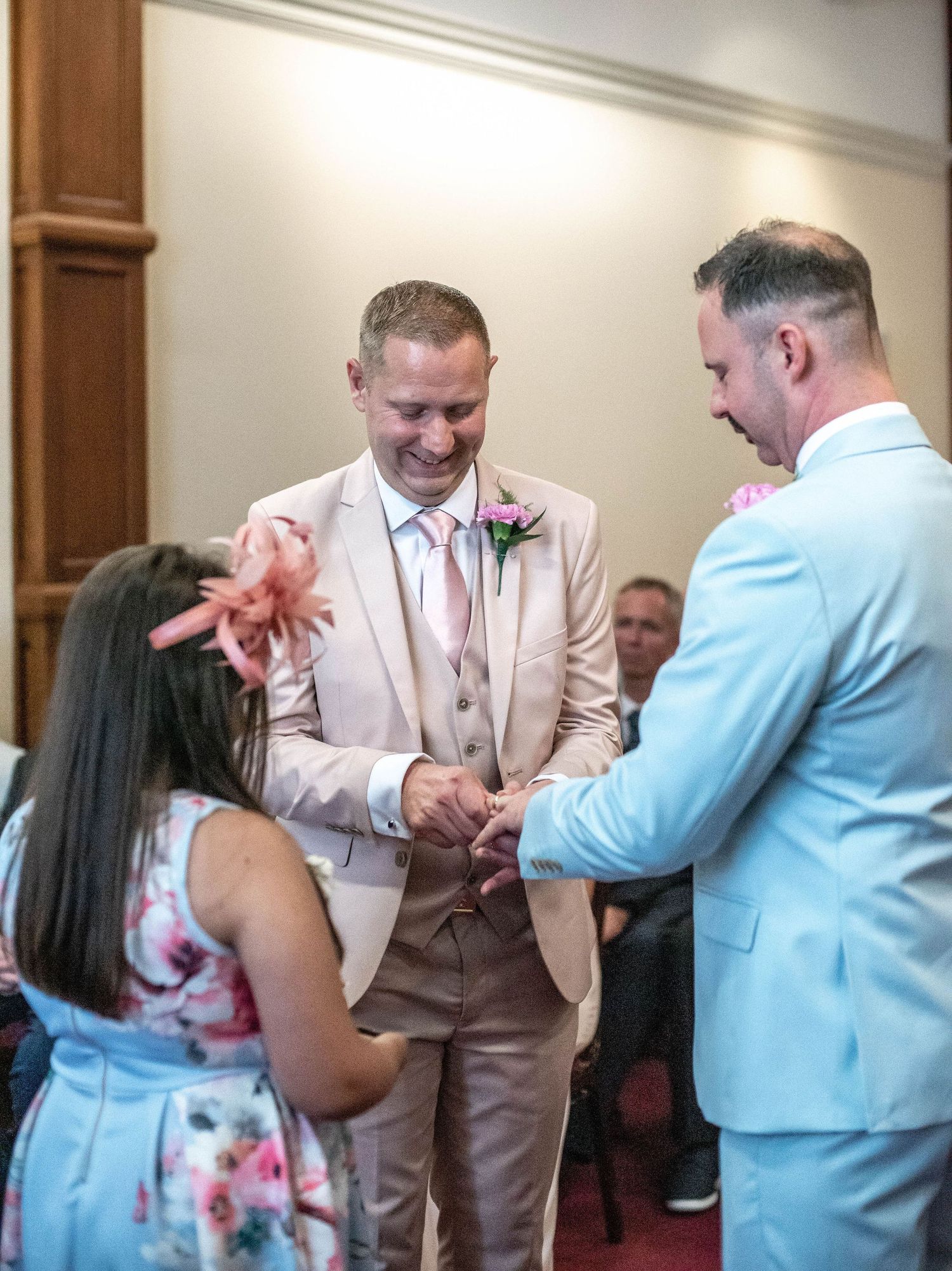 Happy moment during wedding ceremony with guests in pale pink and light blue suits.