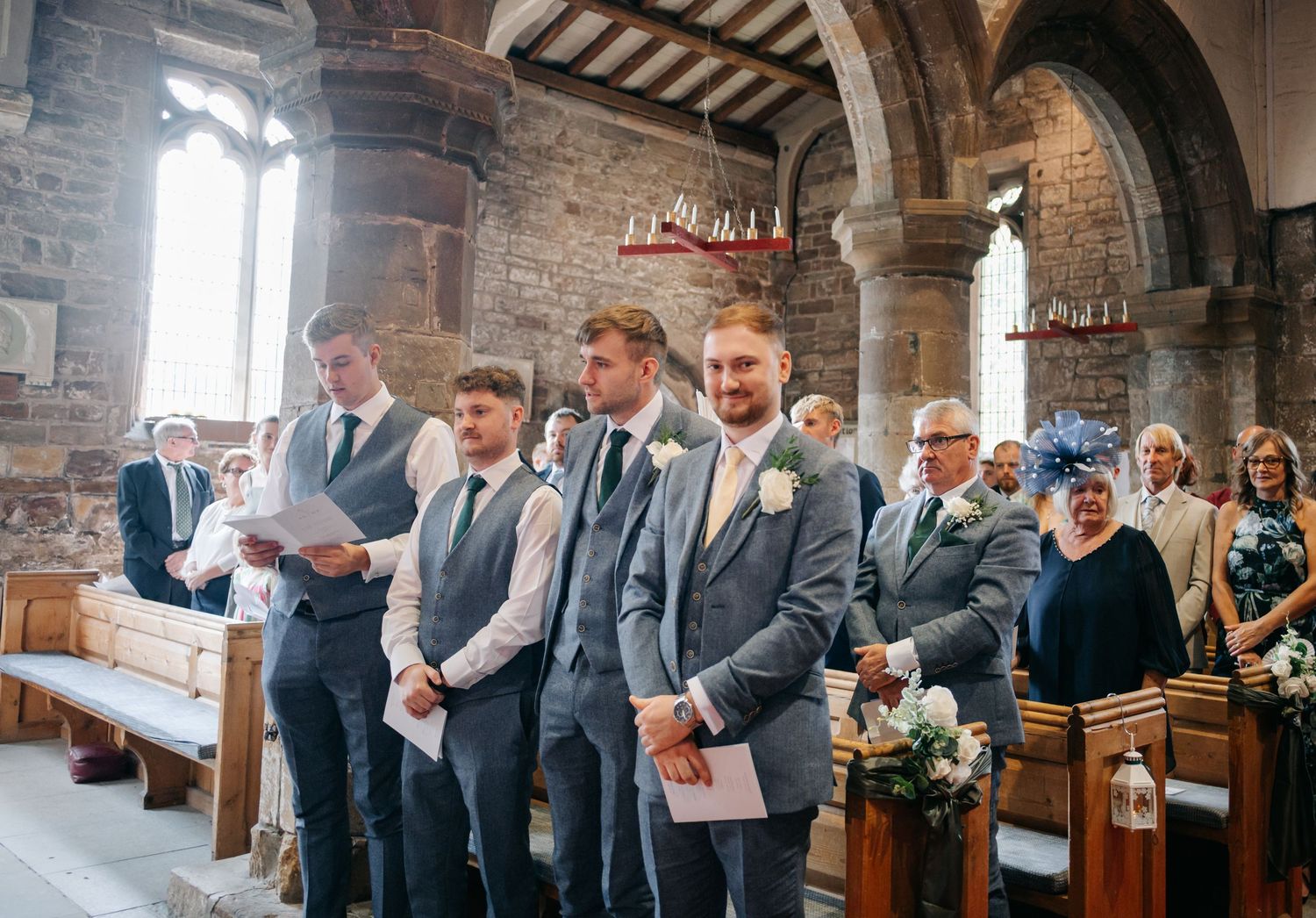 Wedding guests gathered inside a historic stone church with vaulted ceilings and arched windows.