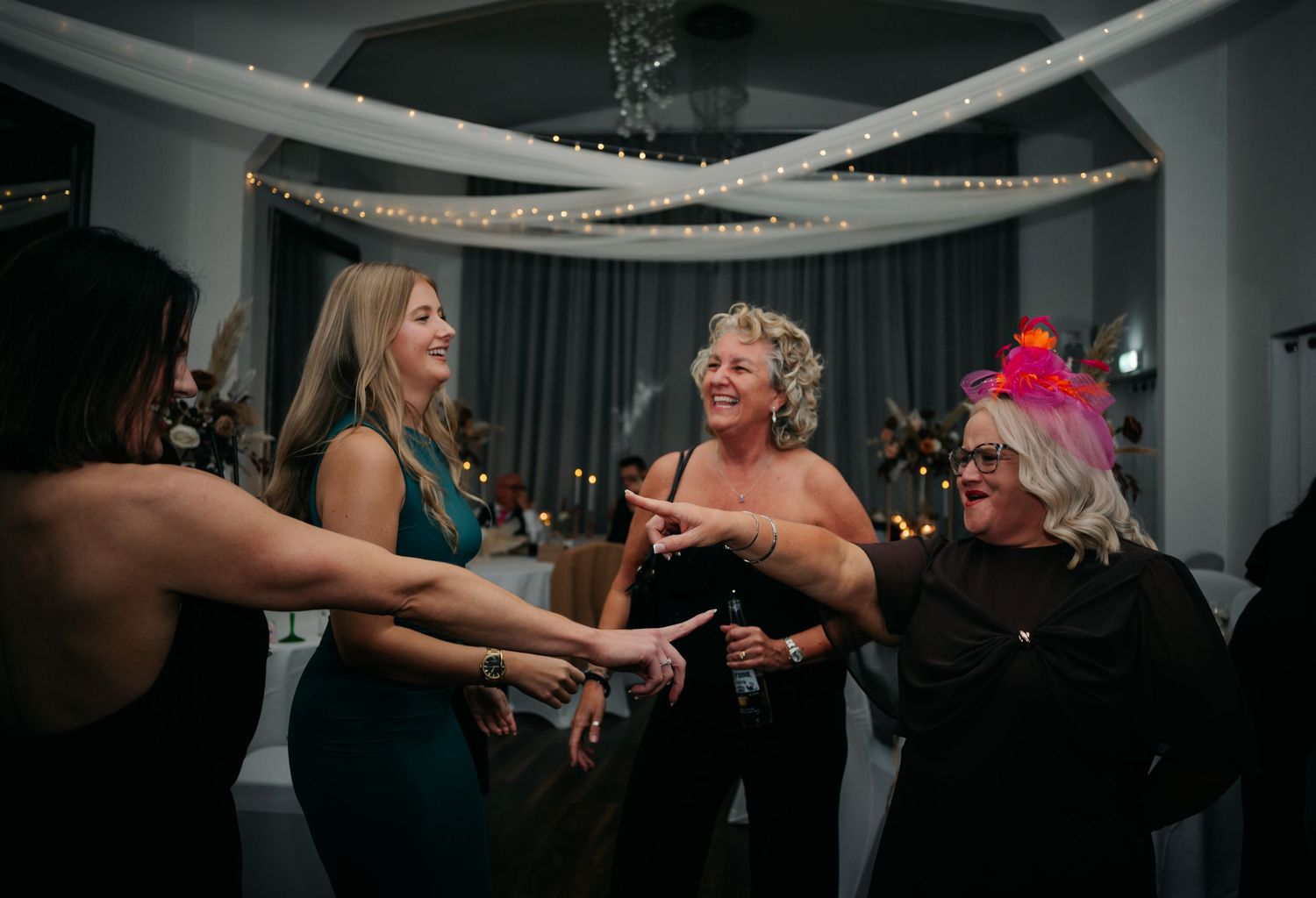 Wedding guests forming a circle on the dance floor during evening celebration.