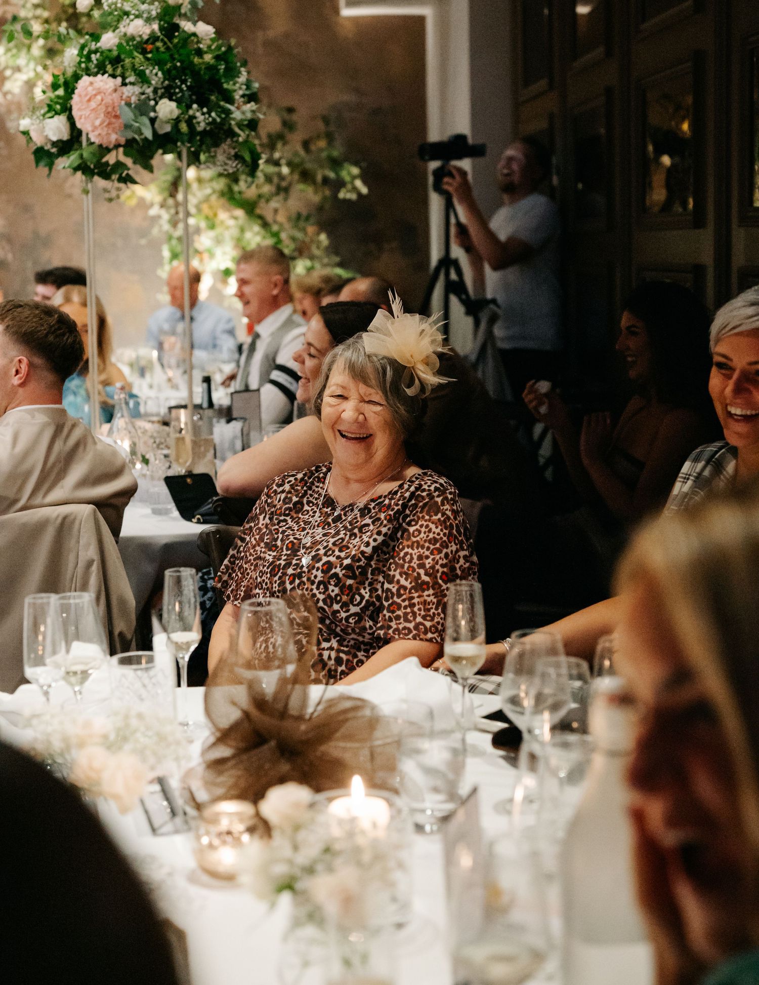 Wedding reception dinner features elegant table settings with floral centerpieces and candlelight.