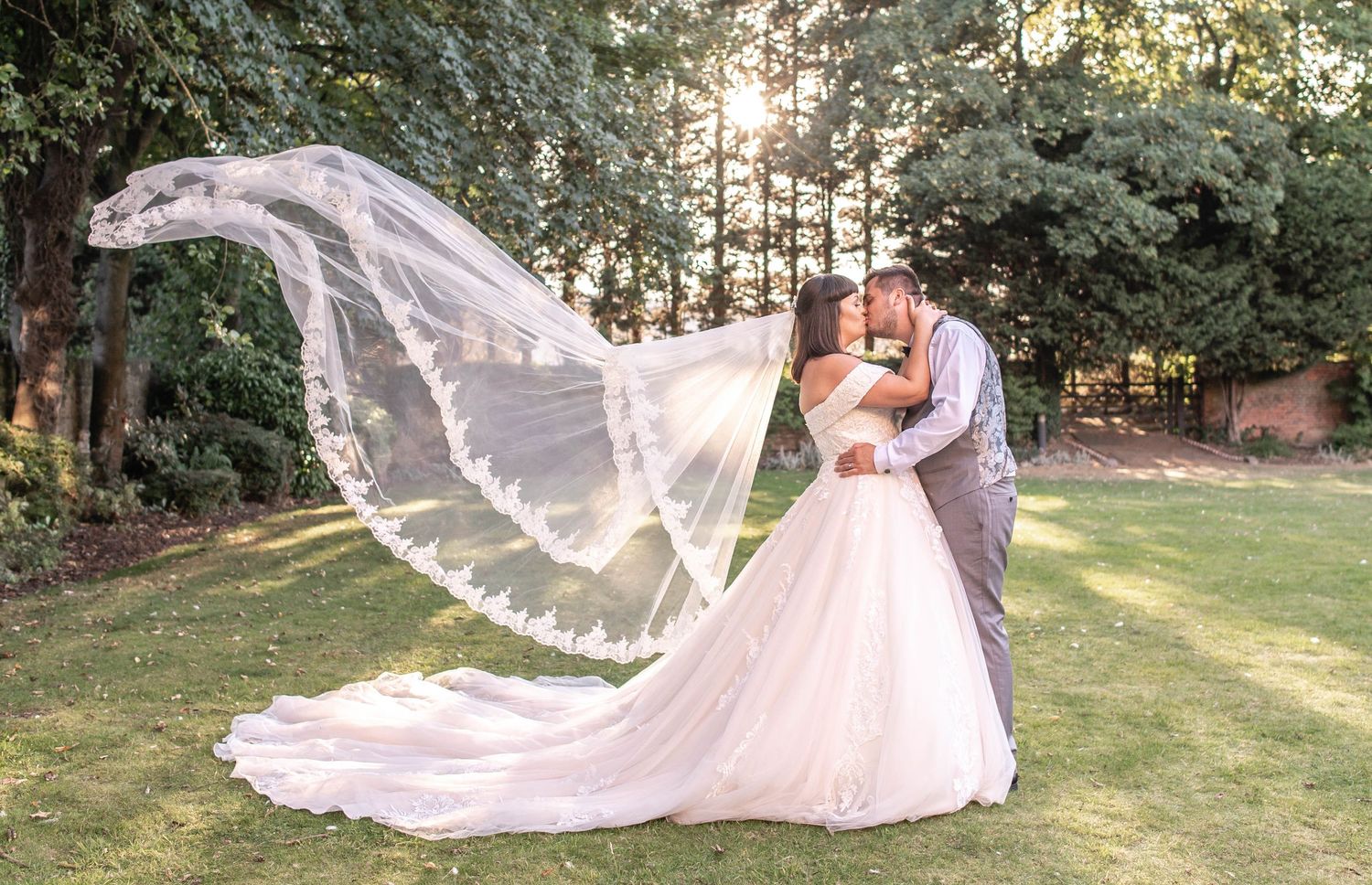 A flowing bridal veil catches the breeze during an outdoor wedding photoshoot.