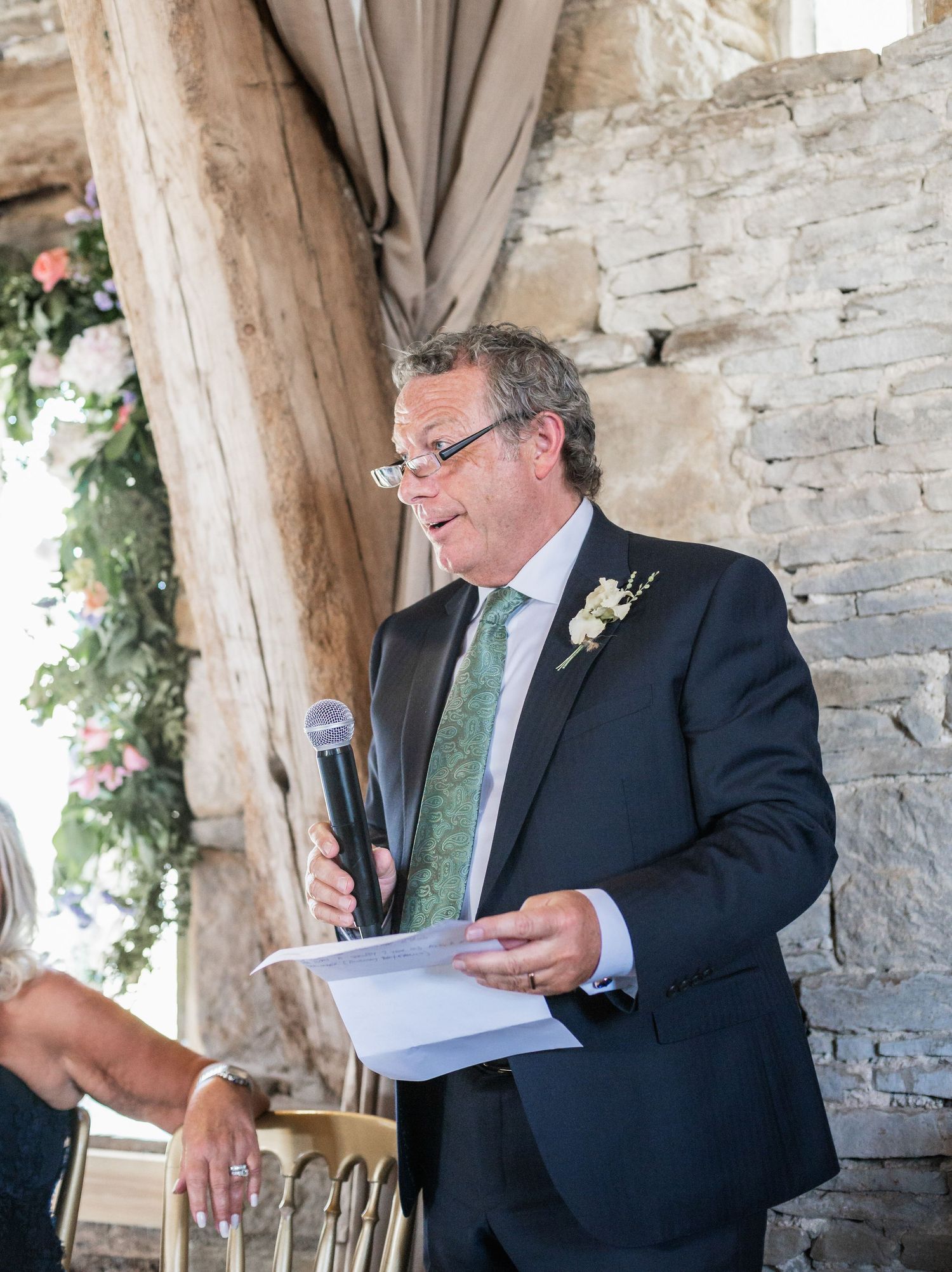 Speaker delivers a wedding speech at a rustic stone venue.