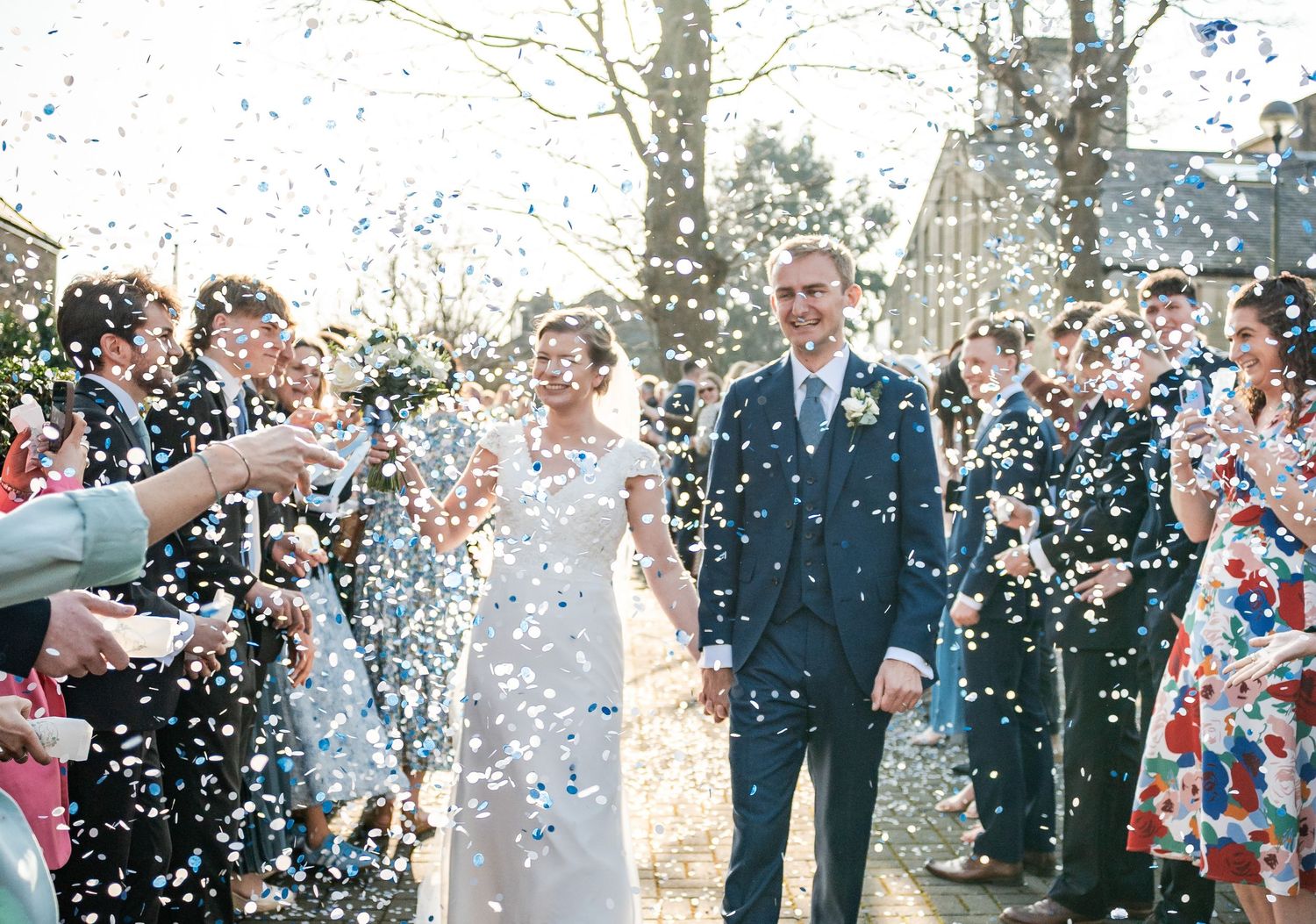 Wedding party celebration outdoors with confetti being thrown during a joyful moment.