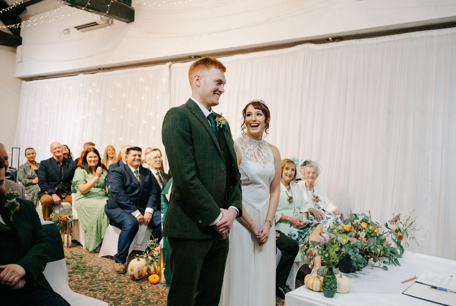 A wedding ceremony in progress with white draping and floral arrangements.