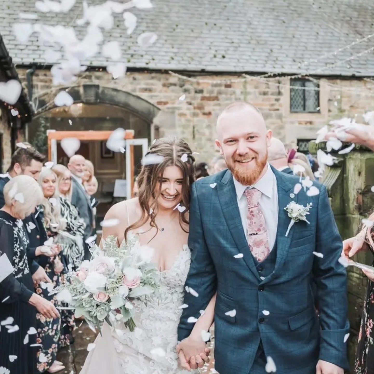 A group of wedding guests celebrate by tossing confetti at the happy couple during an outdoor celebration.