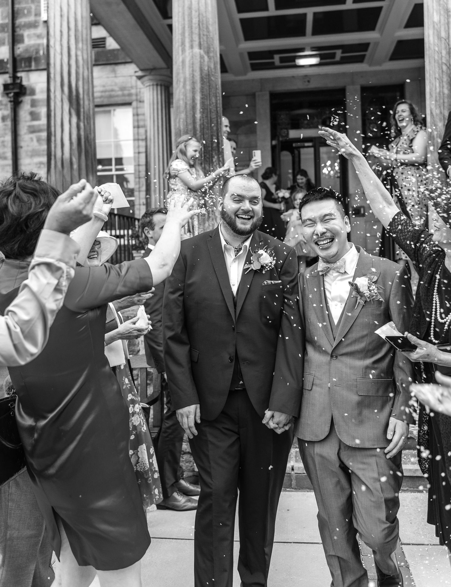 Guests throw confetti over the celebrating couple outside a brick building.