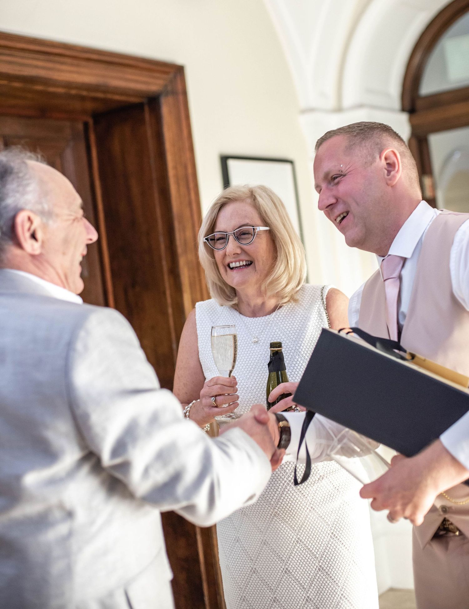 Guests share champagne and laughter during a wedding reception.