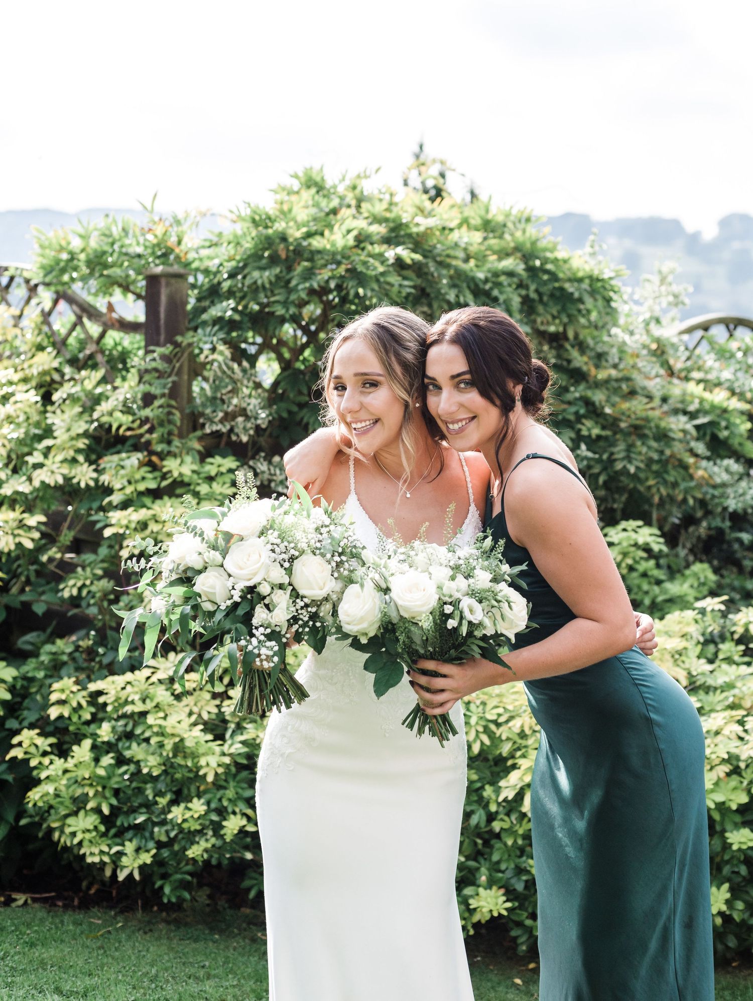Two people sharing a joyful moment with white bouquets in a garden setting.