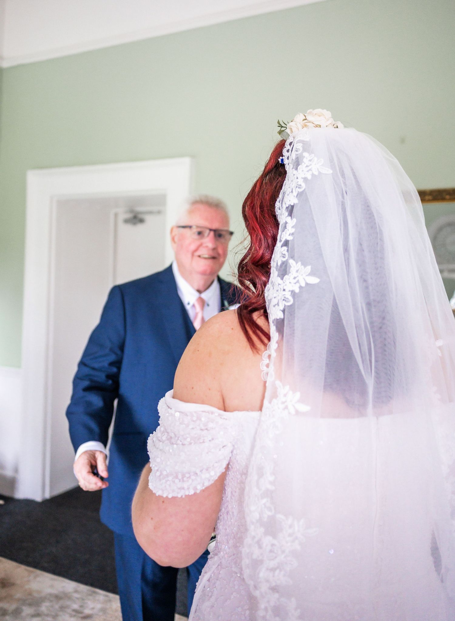 Wedding scene showing a bride in a lace veil and dress with someone in a navy suit.