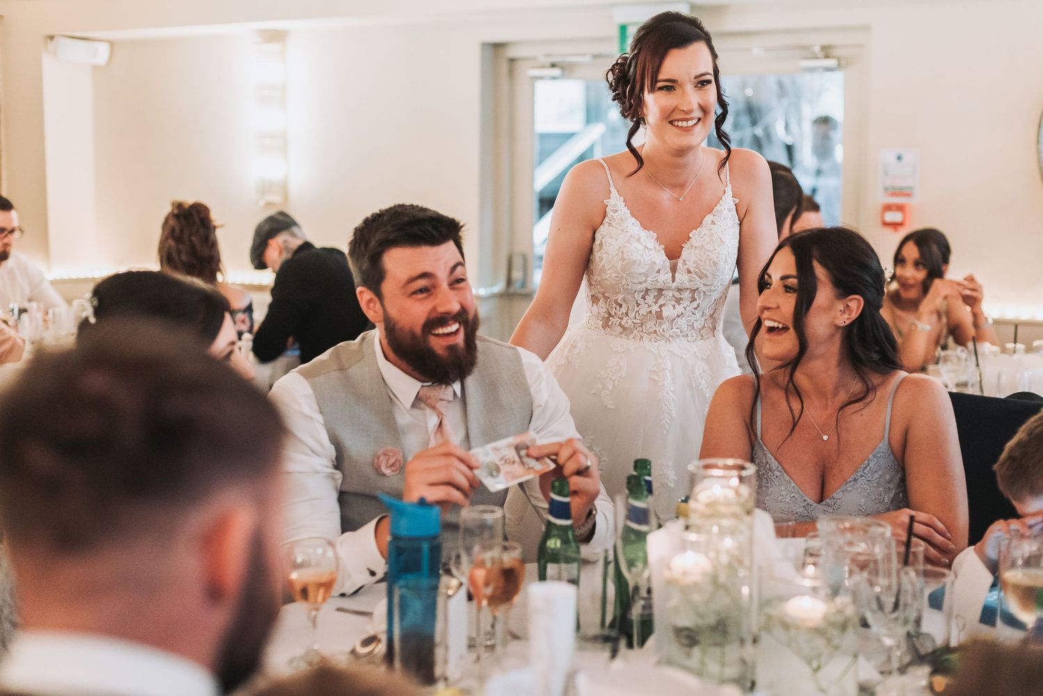 Candid reception moment at a wedding with guests enjoying drinks and conversation at decorated tables.