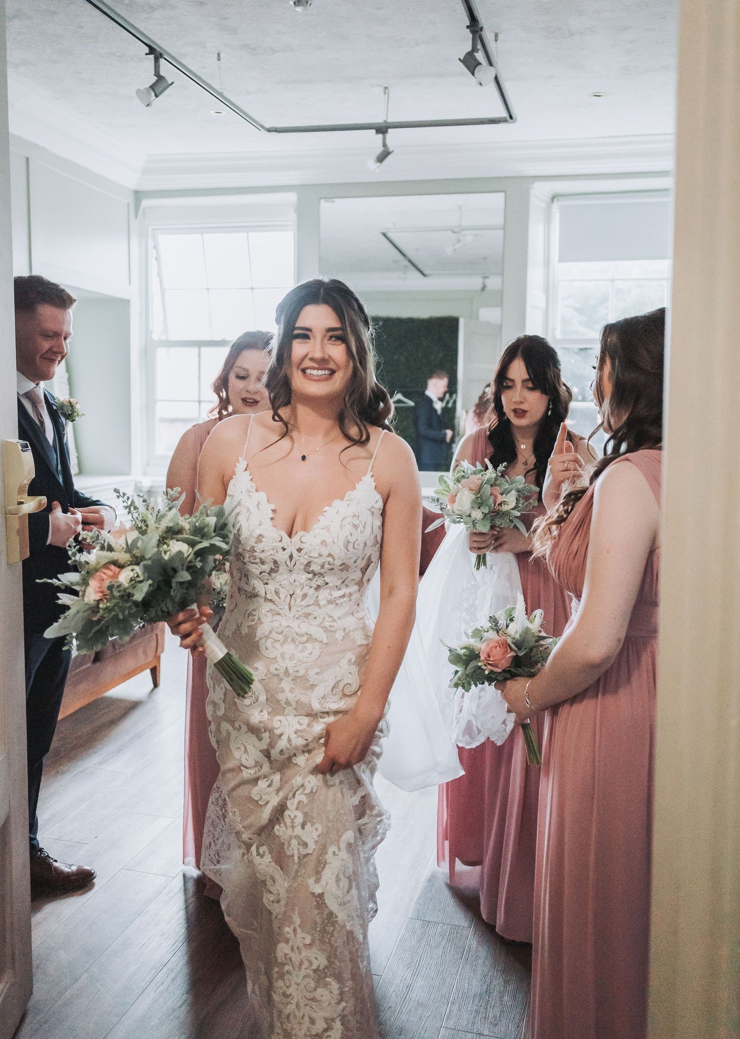 Elegant wedding celebration with bridesmaids in pink dresses and decorative floral bouquets.