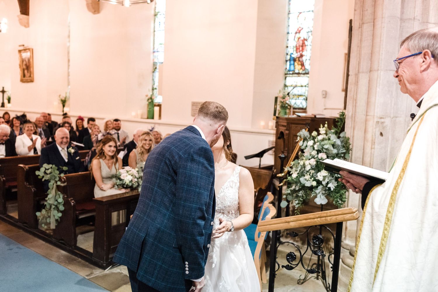 Wedding ceremony taking place in a traditional church with white floral decorations.